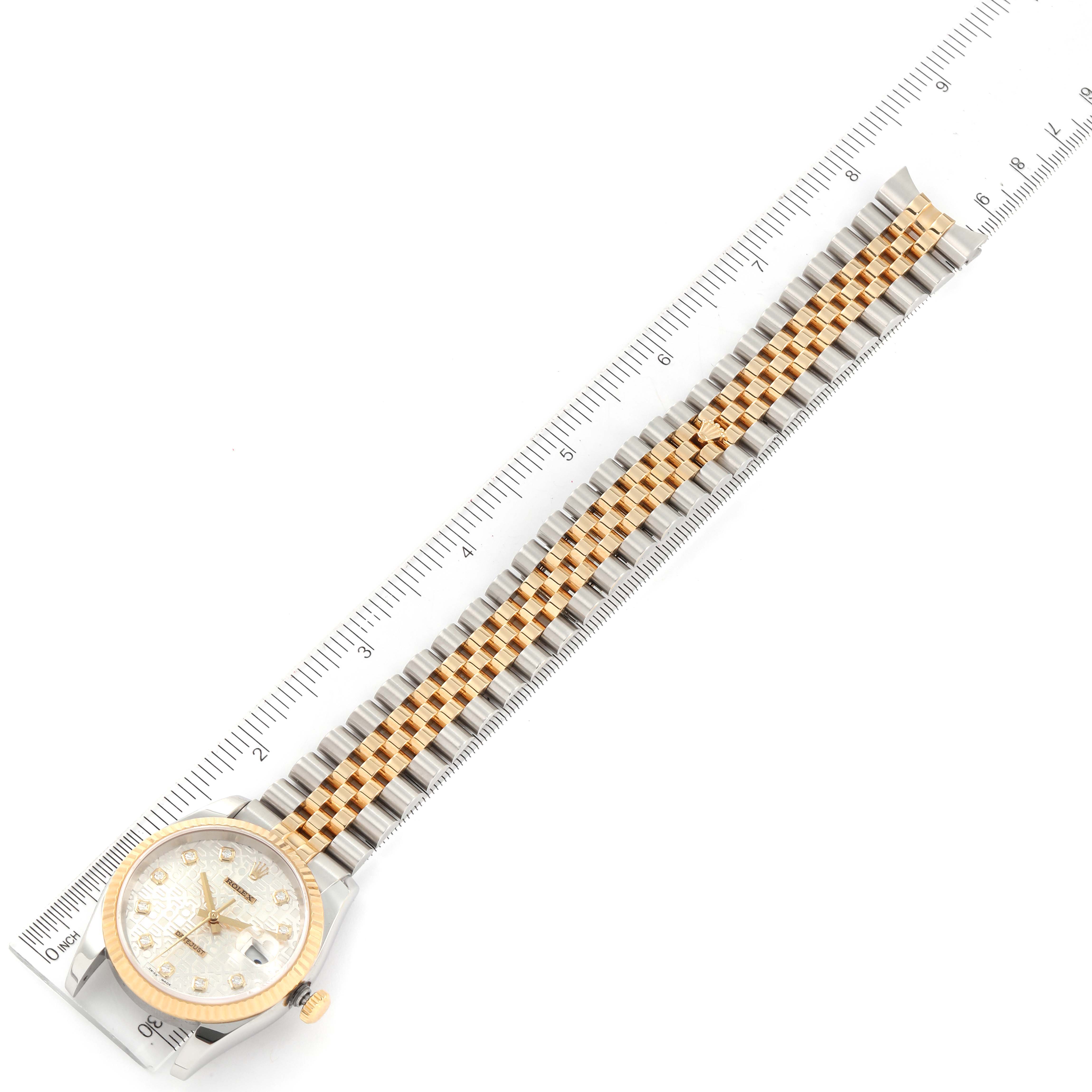 This image shows a top-down view of a Rolex Datejust 116233 Men's Steel and Gold (two tone) Silver Dial 116233 Men's Steel and Gold (two tone) Silver Dial watch, displaying its dial, bezel, and bracelet against a ruler.