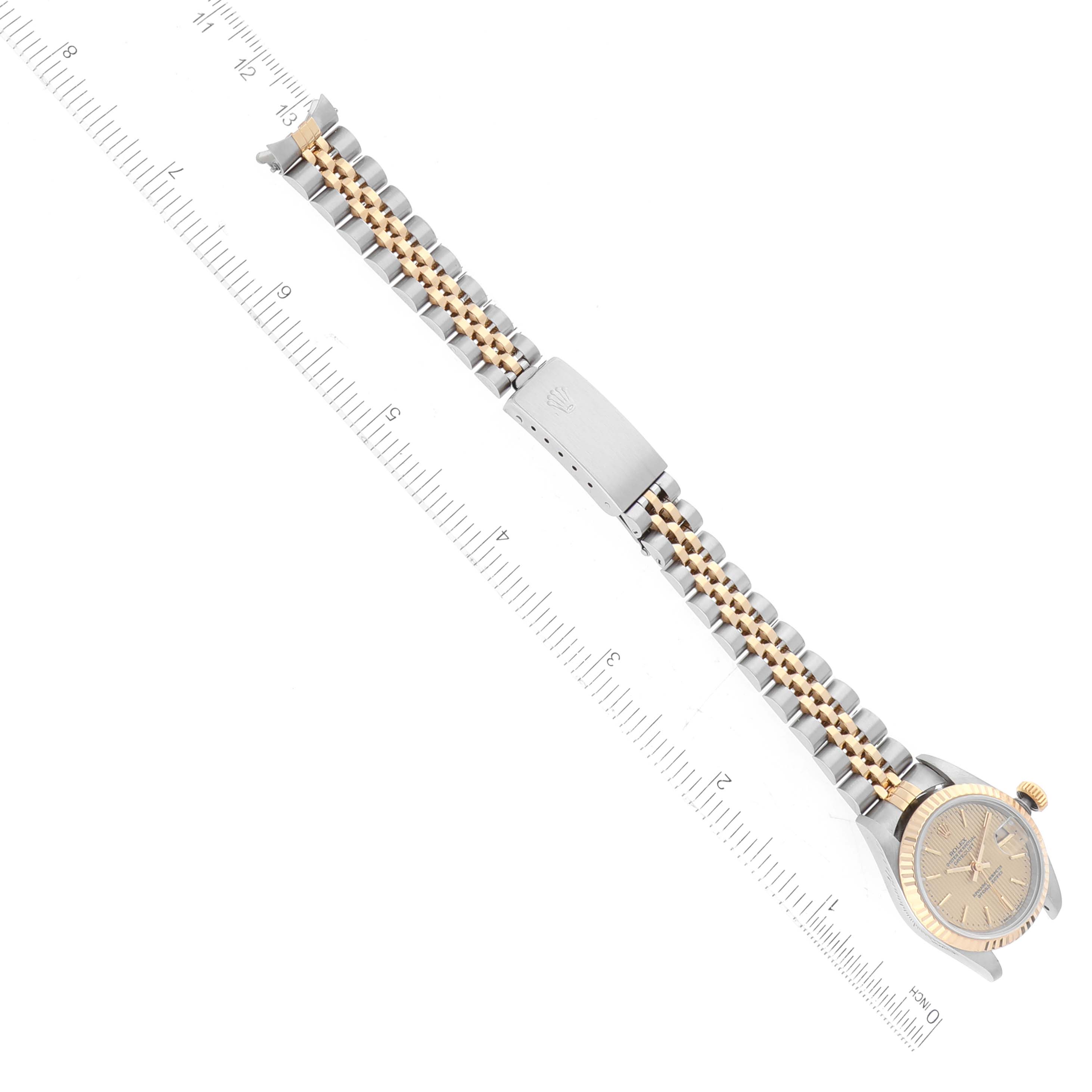 This image shows a Rolex Datejust 69173 Women's Steel and Gold (two tone) Champagne Dial 69173 Women's Steel and Gold (two tone) Champagne Dial watch laid flat, featuring the face, crown, and bracelet, with a ruler for scale.