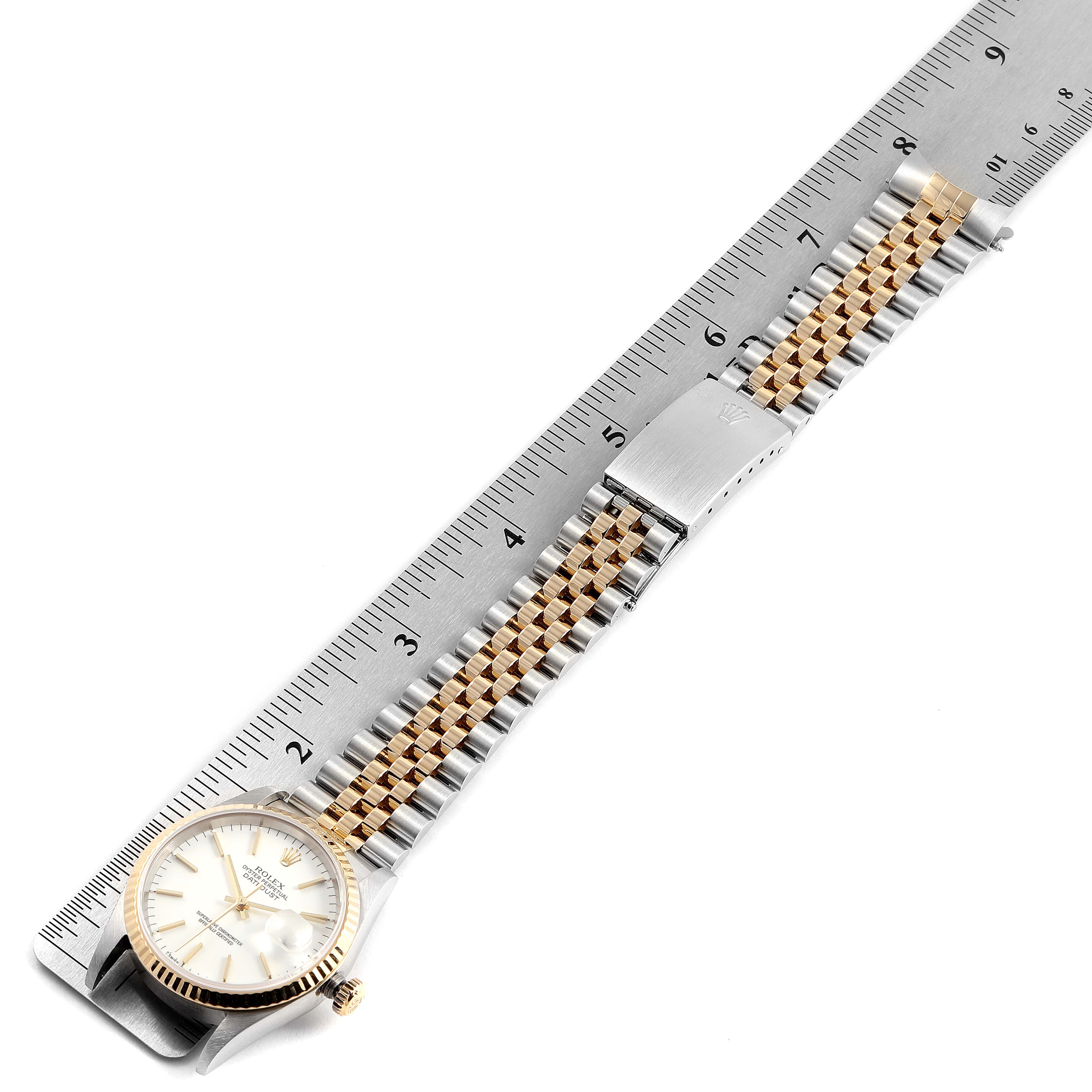 The Rolex Datejust 16233 Men's Steel and Gold (two tone) White Dial 16233 Men's Steel and Gold (two tone) White Dial watch is shown from a top-down angle with the entire strap extended, placed next to a ruler for scale.