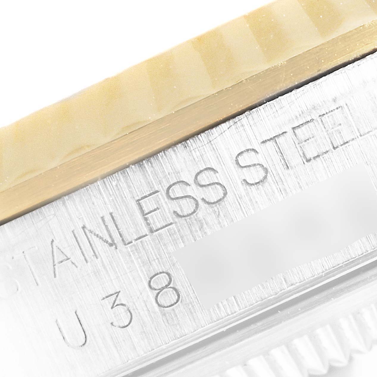 This close-up image of a Rolex Datejust 16233 Men's Steel and Gold (two tone) White Dial 16233 Men's Steel and Gold (two tone) White Dial watch shows the engraved text on the stainless steel case and part of the fluted bezel.