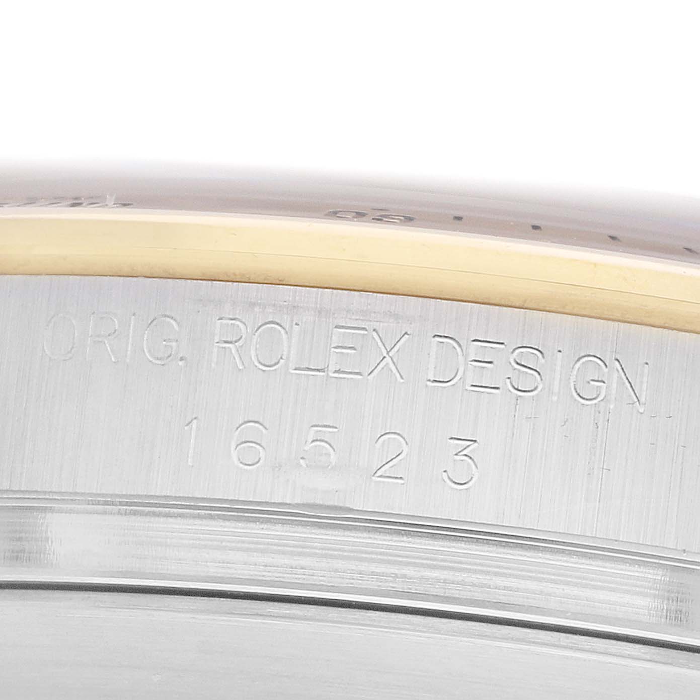 The image shows a close-up of the model number "16523" and "ORIG. ROLEX DESIGN" engraving on the Rolex Daytona 16523 Men
s Steel and Gold (two tone) Black Dial case.