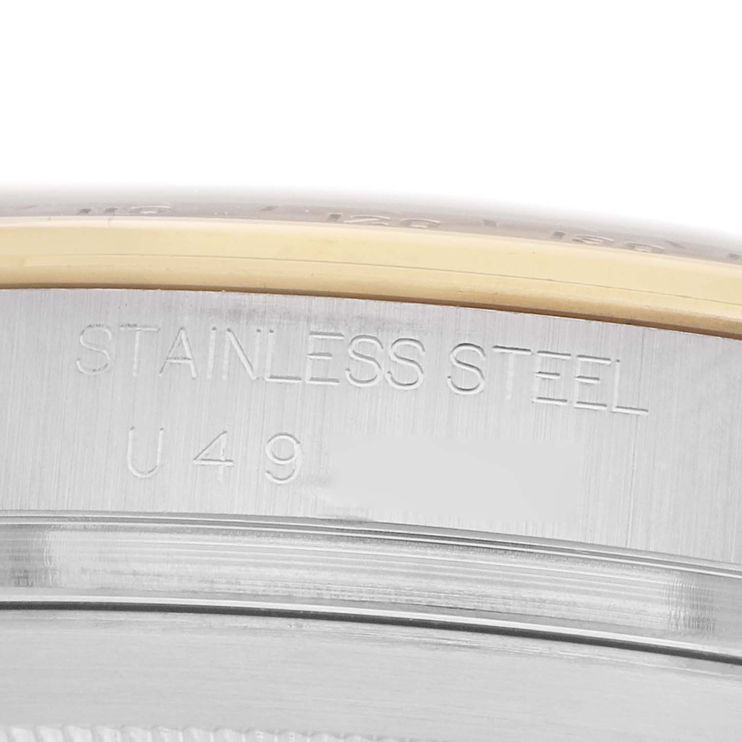 The image shows an angled close-up of the side of a Rolex Daytona 16523 Men
s Steel and Gold (two tone) Black Dial watch case, highlighting "STAINLESS STEEL" engraving.