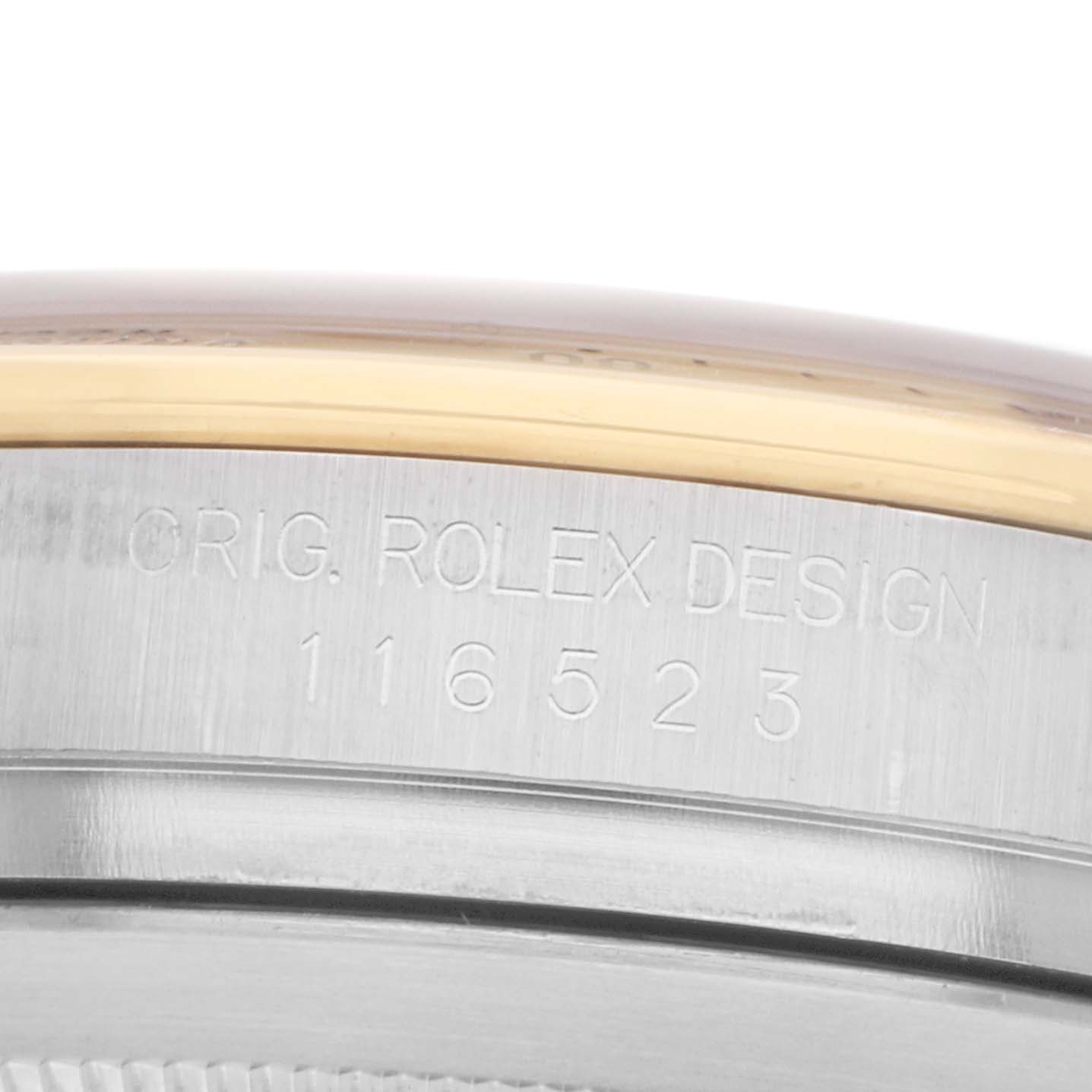 The image shows a close-up side view of the watch case of the Rolex Daytona 116523 Men
s Steel and Gold (two tone) Champagne Dial, featuring engraved design details.