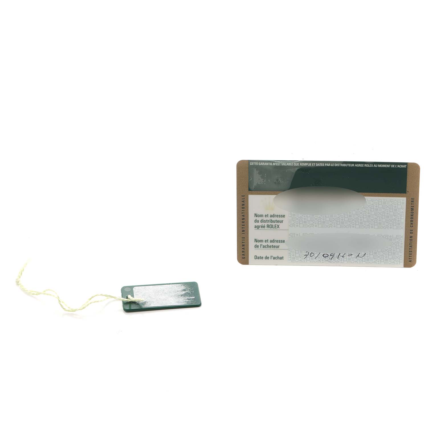 The image shows a warranty card and green tag associated with a Rolex Daytona 116523 Men
s Steel and Gold (two tone) Silver Dial watch.