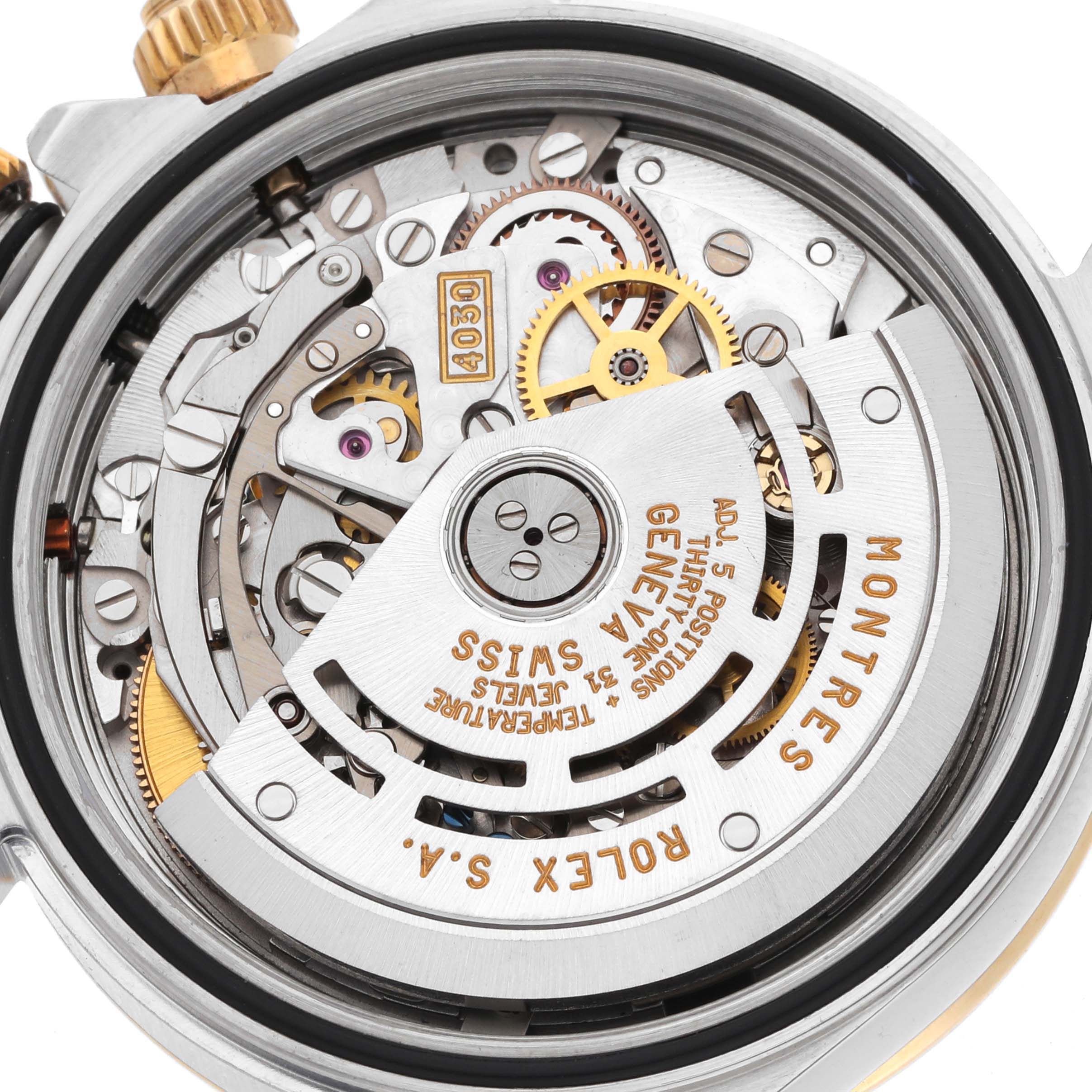 The image shows the movement of a Rolex Daytona 16523 Men
s Steel and Gold (two tone) White Dial, highlighting gears and engravings from a back angle.