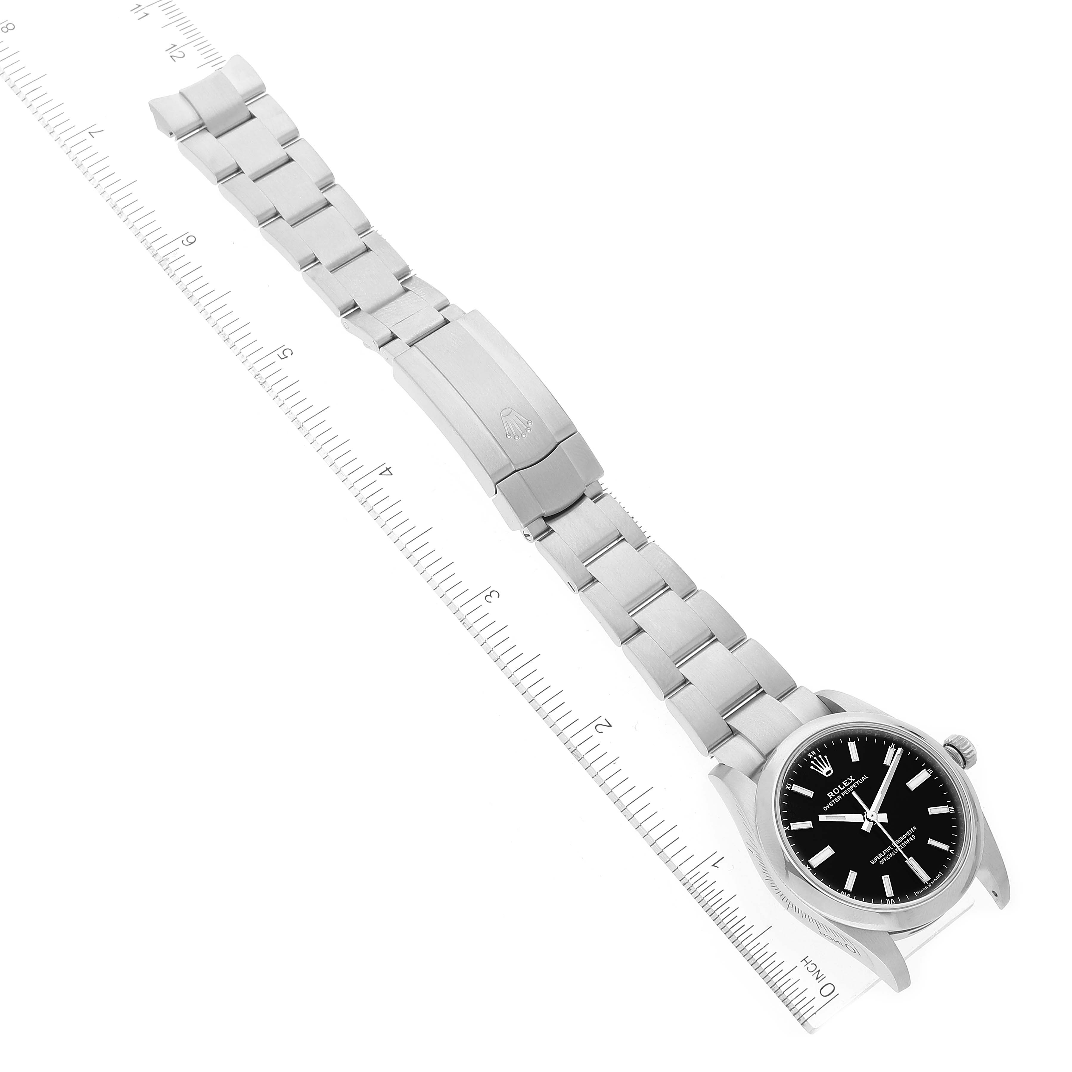 The image shows a top-down view of a Rolex Oyster Perpetual 124200 Men's Stainless Steel Black Dial 124200 Men's Stainless Steel Black Dial watch, including its full bracelet and clasp, placed along a measuring scale.
