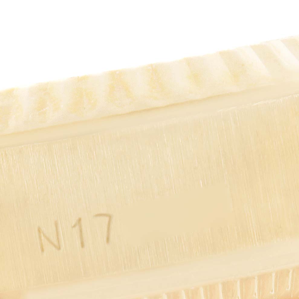 This close-up image of a Rolex President 69178 Women's Yellow Gold Silver Dial 69178 Women's Yellow Gold Silver Dial model watch shows the fluted bezel and part of the case with the engraving "N17."
