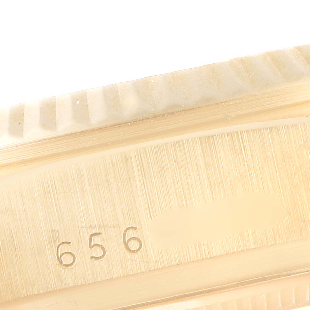 This close-up of a Rolex President 18038 Men
s Yellow Gold Champagne Dial 18038 Men
s Yellow Gold Champagne Dial model watch shows the side of the case with part of the fluted bezel and a serial number engraving.