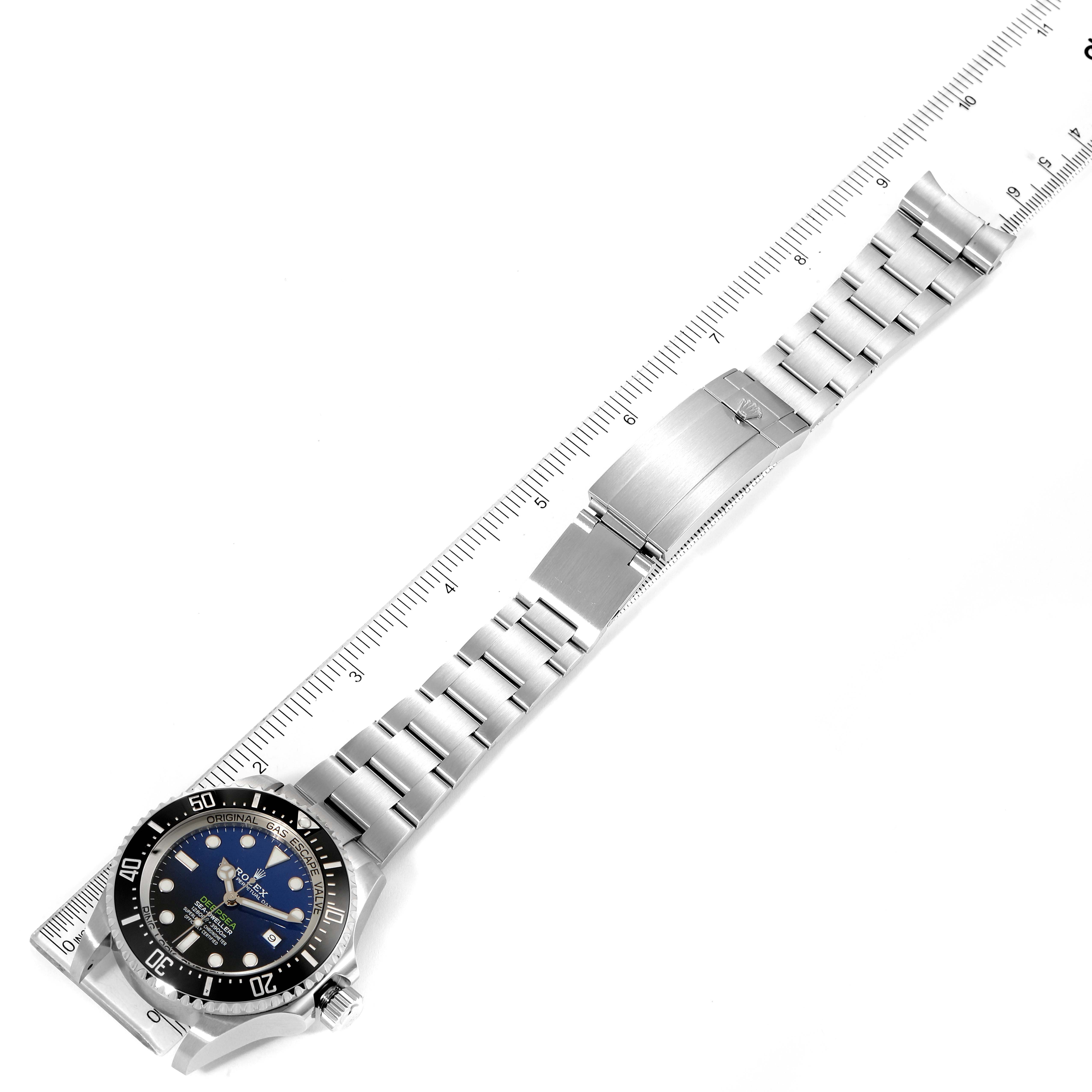 This image shows the entire Rolex Sea-Dweller 126660 Men's Stainless Steel Blue Dial 126660 Men's Stainless Steel Blue Dial watch, laid flat next to a ruler, from an aerial view.