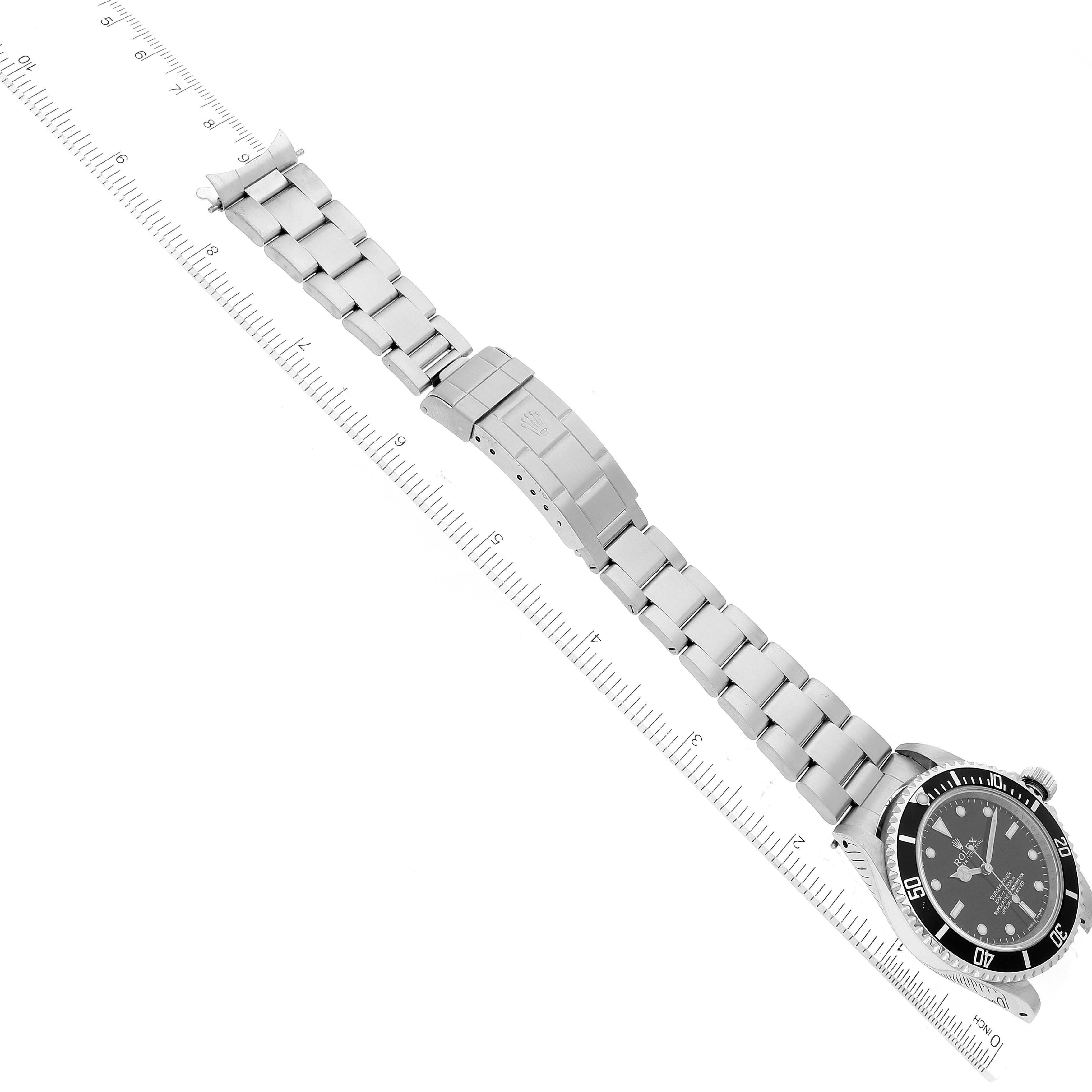 The image shows the front view of a Rolex Submariner 14060 Men's Stainless Steel Black Dial 14060 Men's Stainless Steel Black Dial watch and its stainless steel bracelet fully extended, aligned with a ruler for scale.