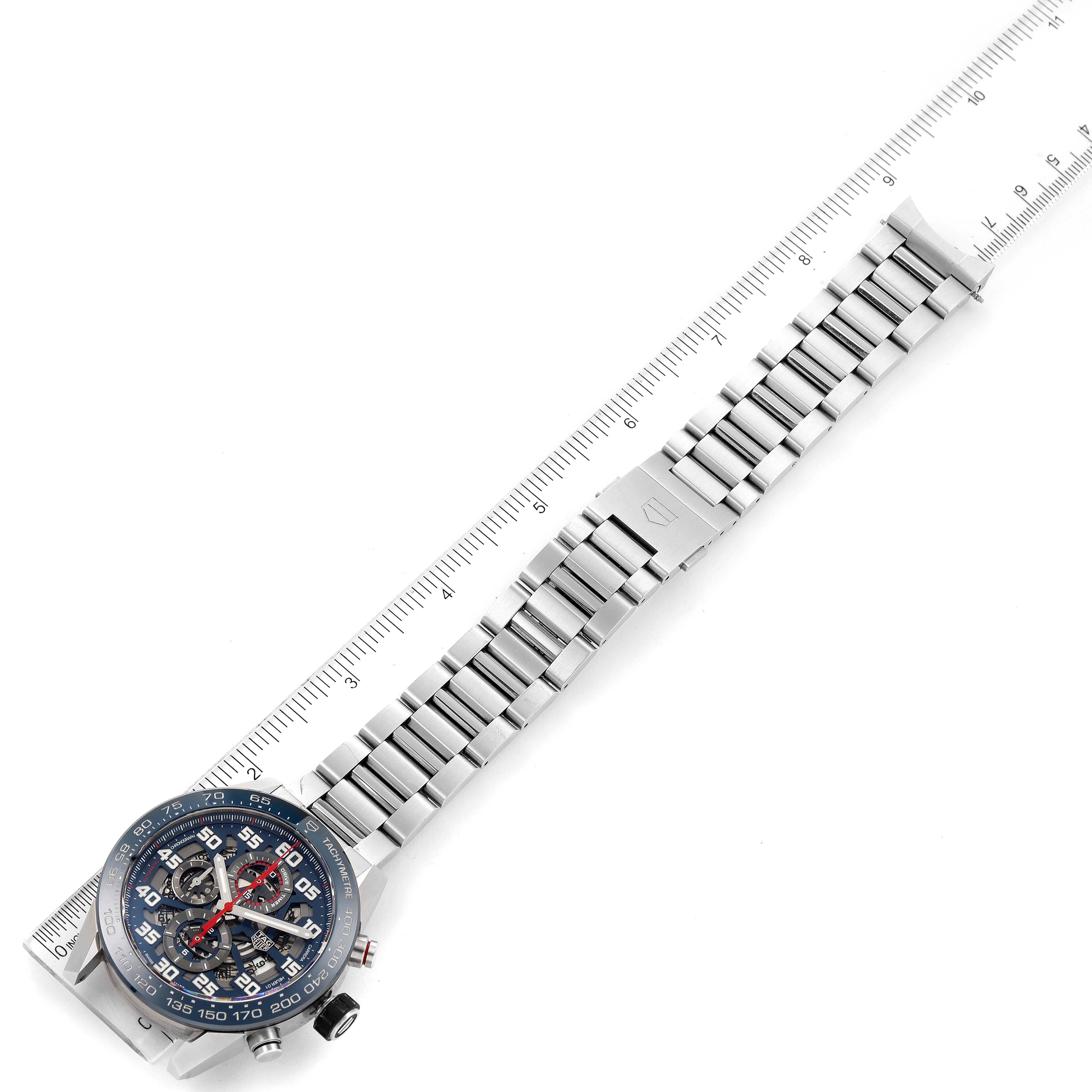 The image shows a Tag Heuer Carrera CAR2A1K.BA0703 Men's Stainless Steel Blue Dial CAR2A1K.BA0703 Men's Stainless Steel Blue Dial watch laid flat, displaying its face and metal bracelet along a ruler.
