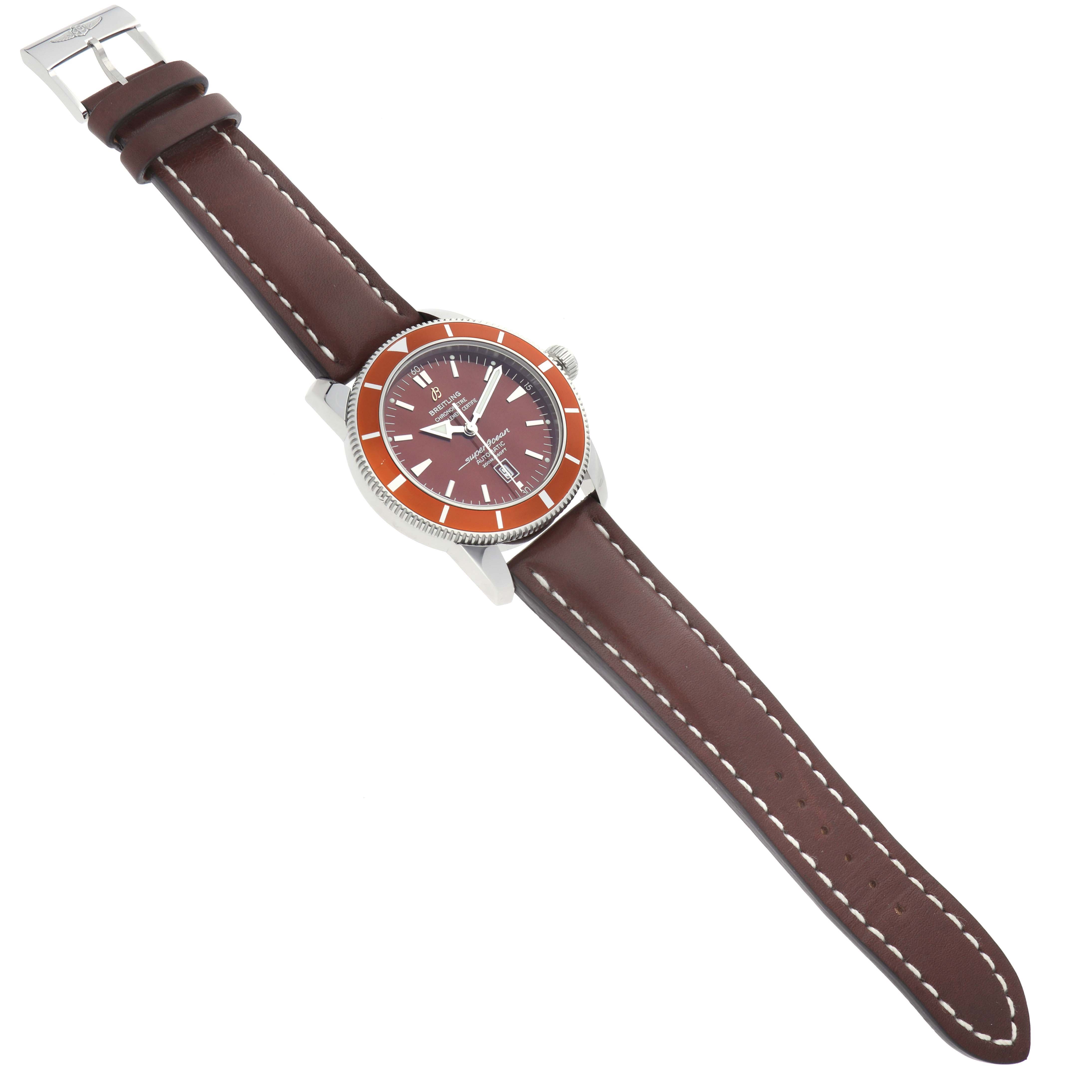The Breitling Superocean A17320 Men
s Stainless Steel Brown Dial watch is shown from an overhead angle, displaying the face, bezel, and leather strap with stitching.