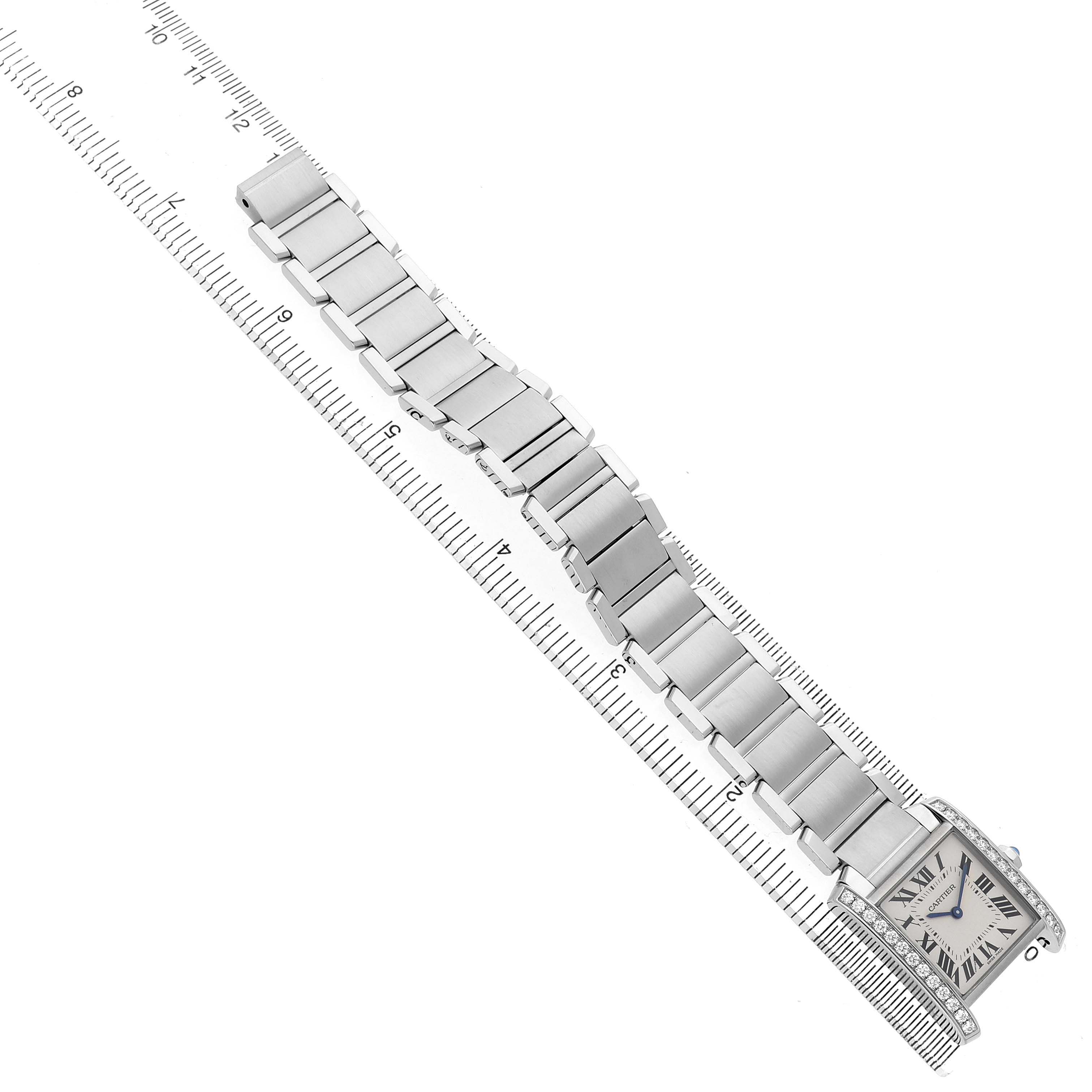 The Cartier Tank Francaise W4TA0009 Women's Stainless Steel Silver Dial watch is shown from a top-down angle featuring the complete bracelet and face next to a ruler.