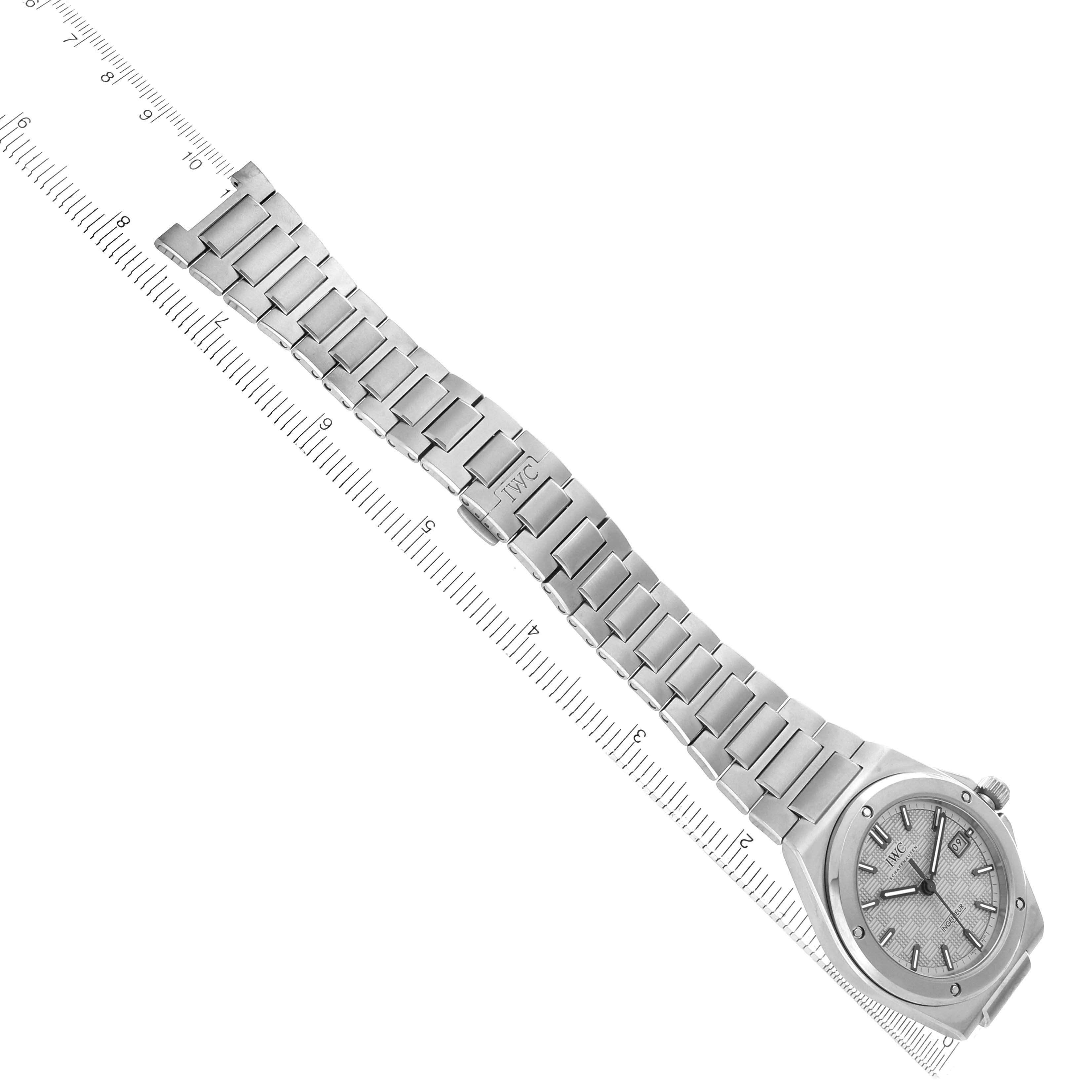 The IWC Ingenieur IW328904 Men
s Titanium Grey Dial watch is shown from an angled top view, displaying its face, bracelet, and clasp on a ruler.