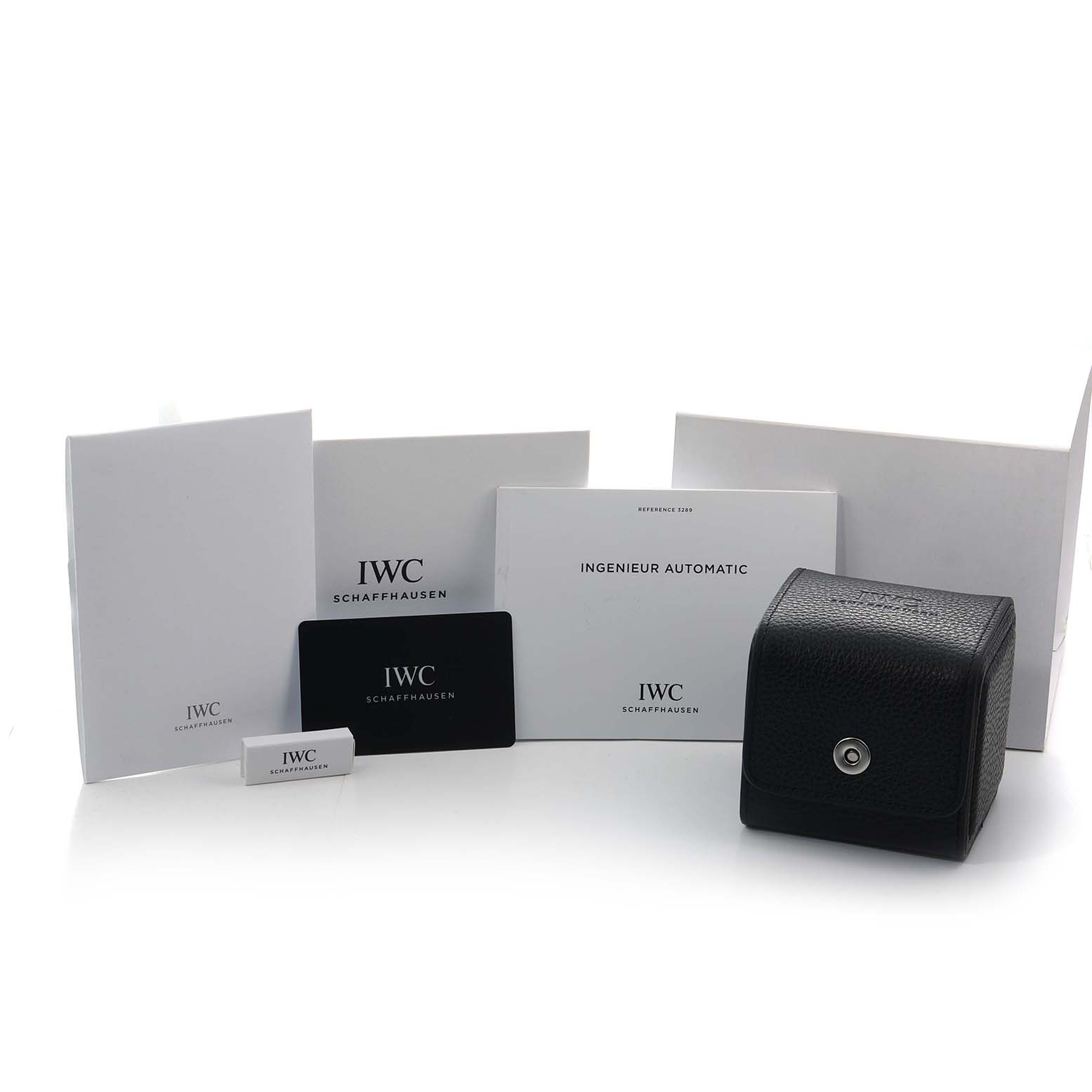 The image shows the packaging and accessories of the IWC Ingenieur IW328904 Men
s Titanium Grey Dial, including manuals, a warranty card, and a leather case.