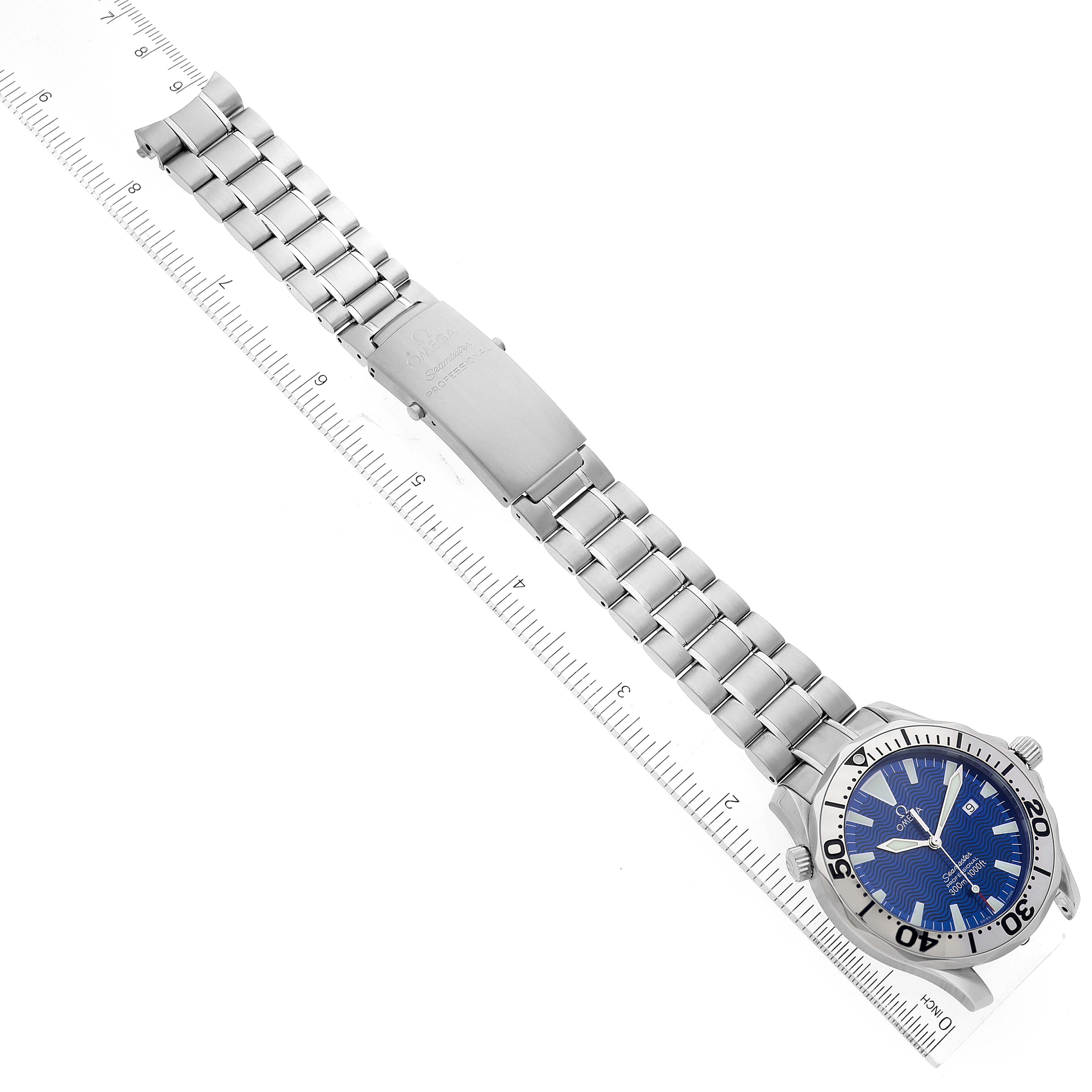 The Omega Seamaster 2265.80.00 Men's Stainless Steel Blue Dial 2265.80.00 Men's Stainless Steel Blue Dial watch is shown from an overhead angle, displaying its bracelet, clasp, and blue dial with a ruler alongside it.