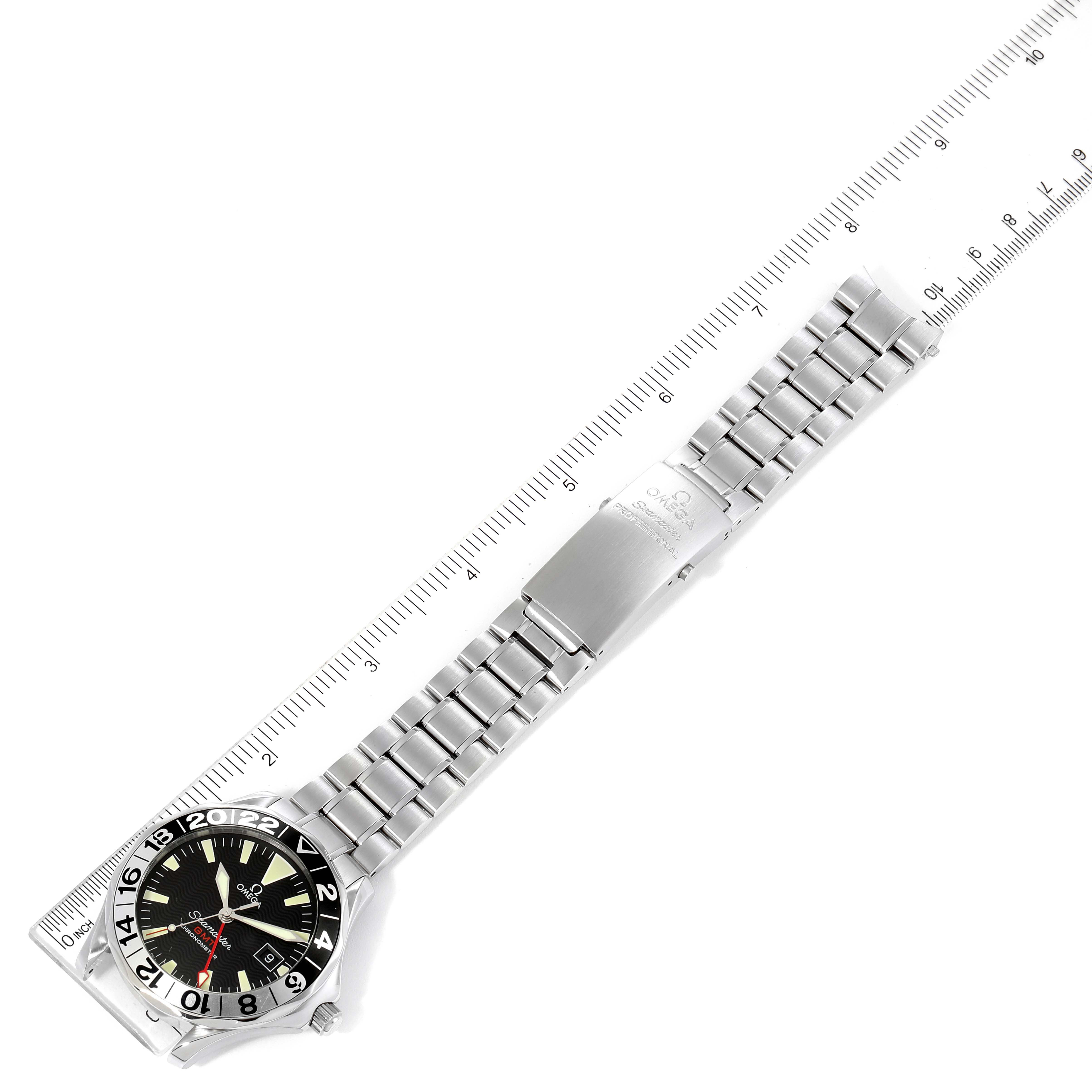 The image shows a top-down view of an Omega Seamaster 2234.50.00 Men's Stainless Steel Black Dial 2234.50.00 Men's Stainless Steel Black Dial watch with a stainless steel bracelet and a ruler for scale.