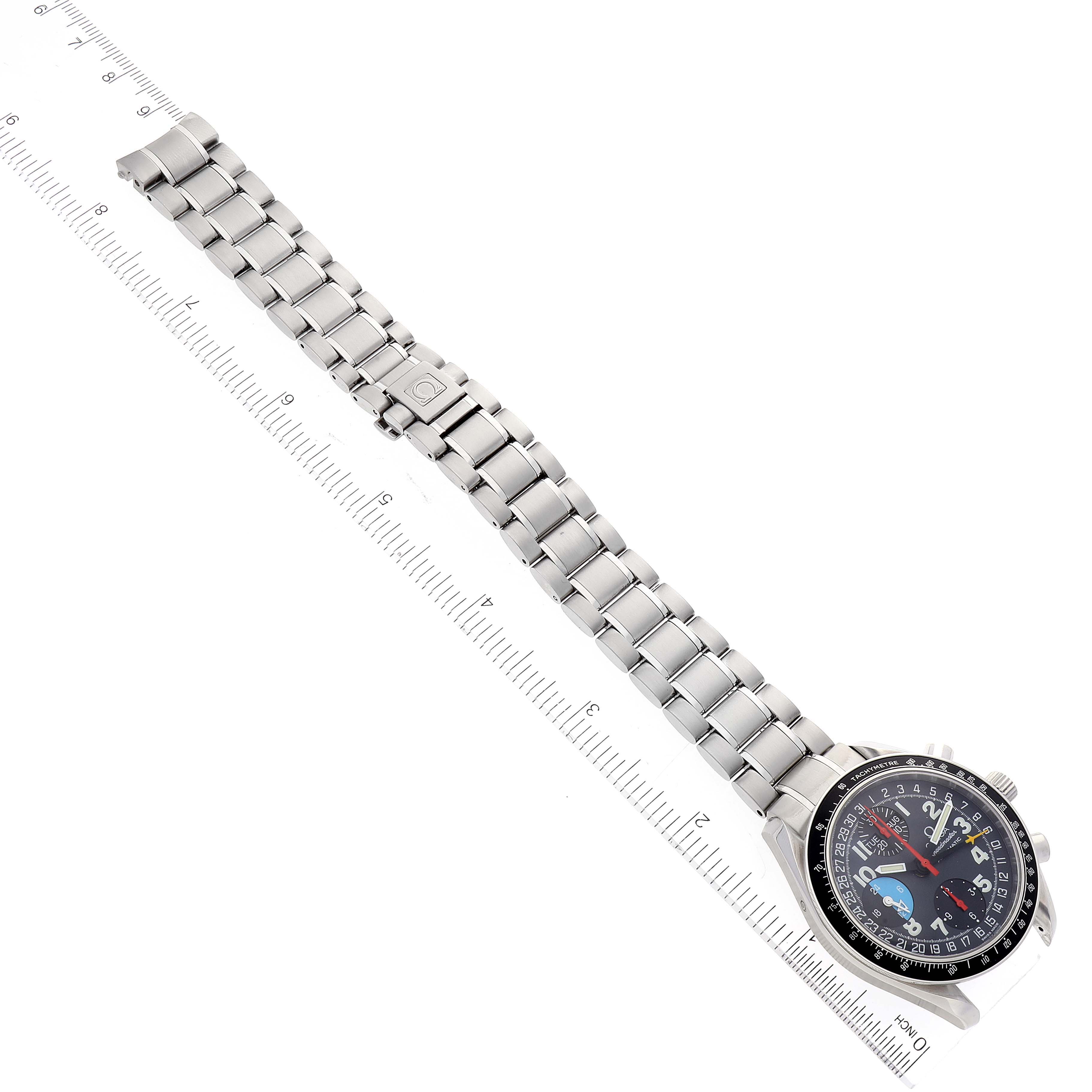 The image shows an Omega Speedmaster 3520.53.00 Men
s Stainless Steel Grey Dial 3520.53.00 Men
s Stainless Steel Grey Dial watch with a metal bracelet, positioned diagonally alongside a measuring ruler.