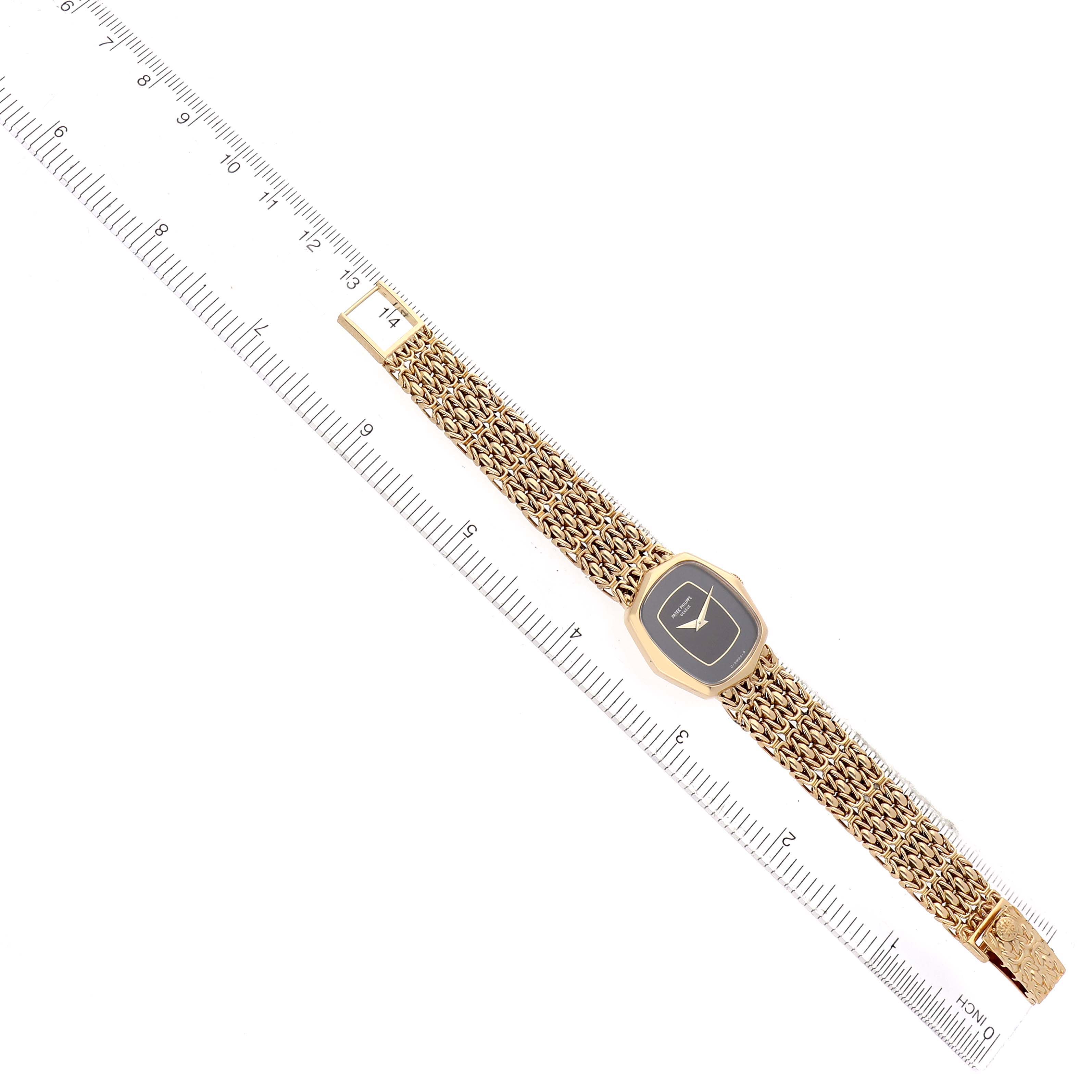 The Patek Philippe Vintage 4460J Women's Yellow Gold Black Dial watch is displayed flat from a top-down angle, showing the entire bracelet and face along with a ruler for scale.