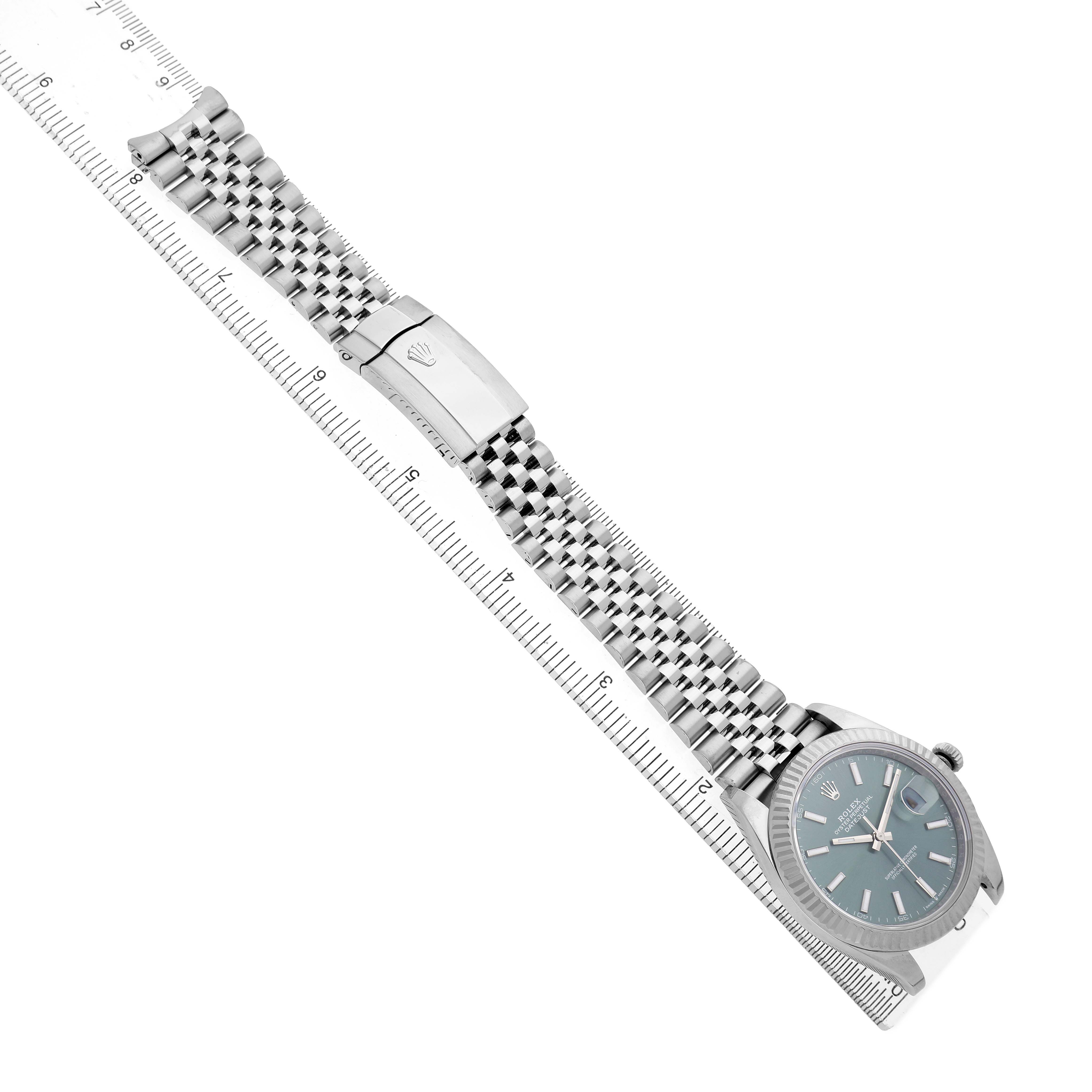 The Rolex Datejust 41 126334 Men's Stainless Steel Green Dial watch is shown at an angle displaying the face, bracelet, and clasp, aligned with a ruler.