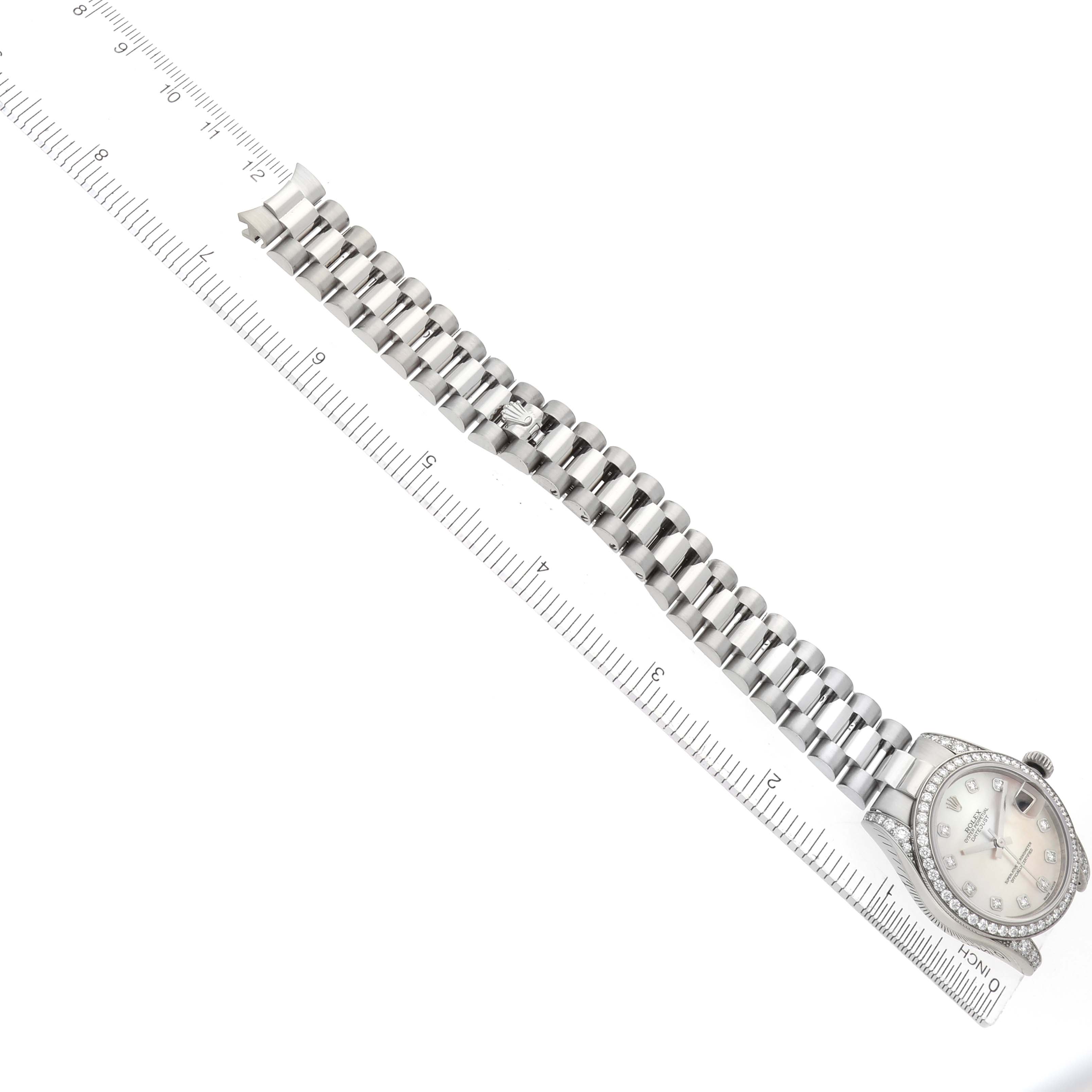 The Rolex President 178159 Women
s White Gold Mother of Pearl Dial watch is shown from a top view, displaying the dial, case, and bracelet laid next to a ruler for scale.