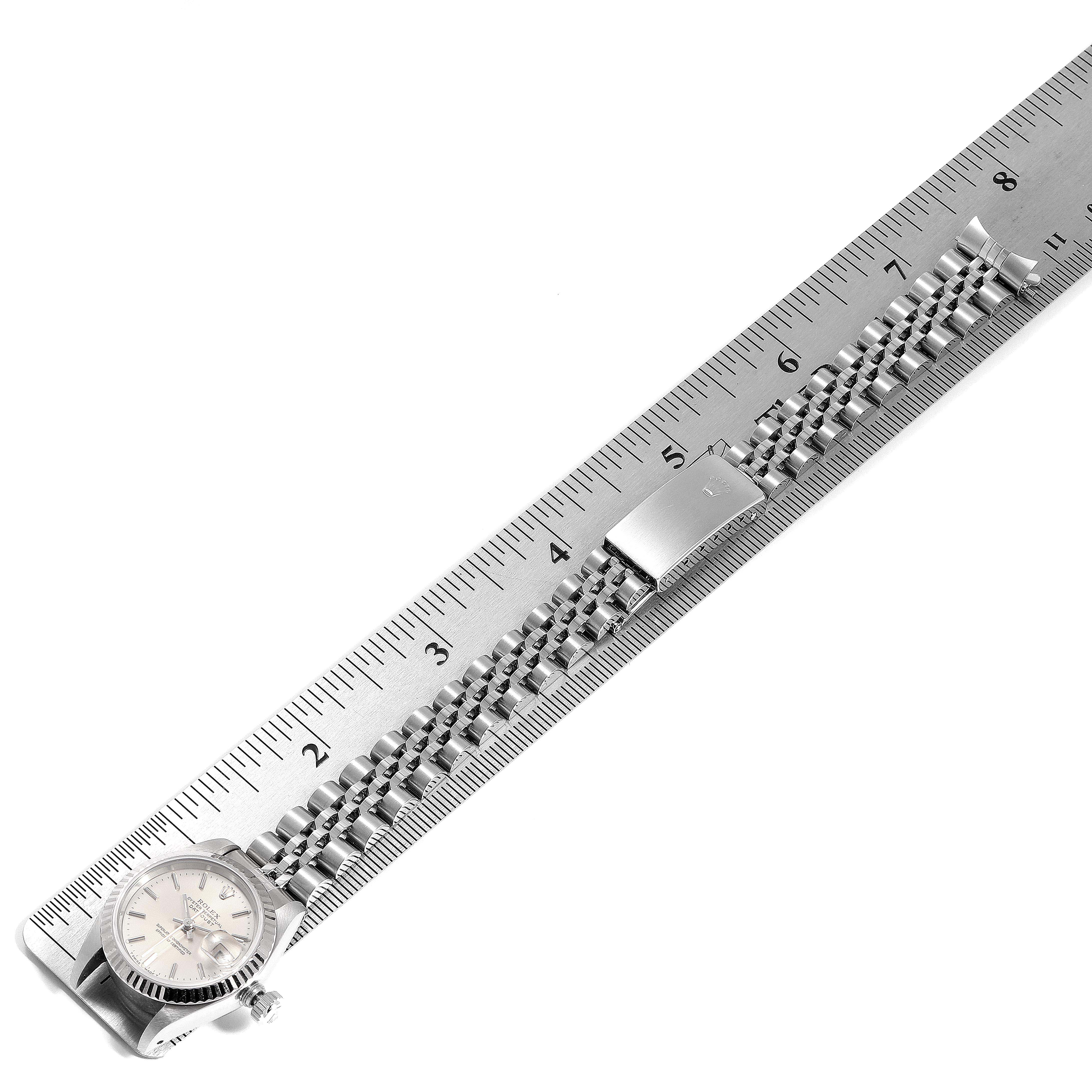 The Rolex Datejust 69174 Women
s Stainless Steel Silver Dial 69174 Women
s Stainless Steel Silver Dial watch is shown from a top-down angle, featuring its face, bracelet, and clasp, next to a ruler for scale.