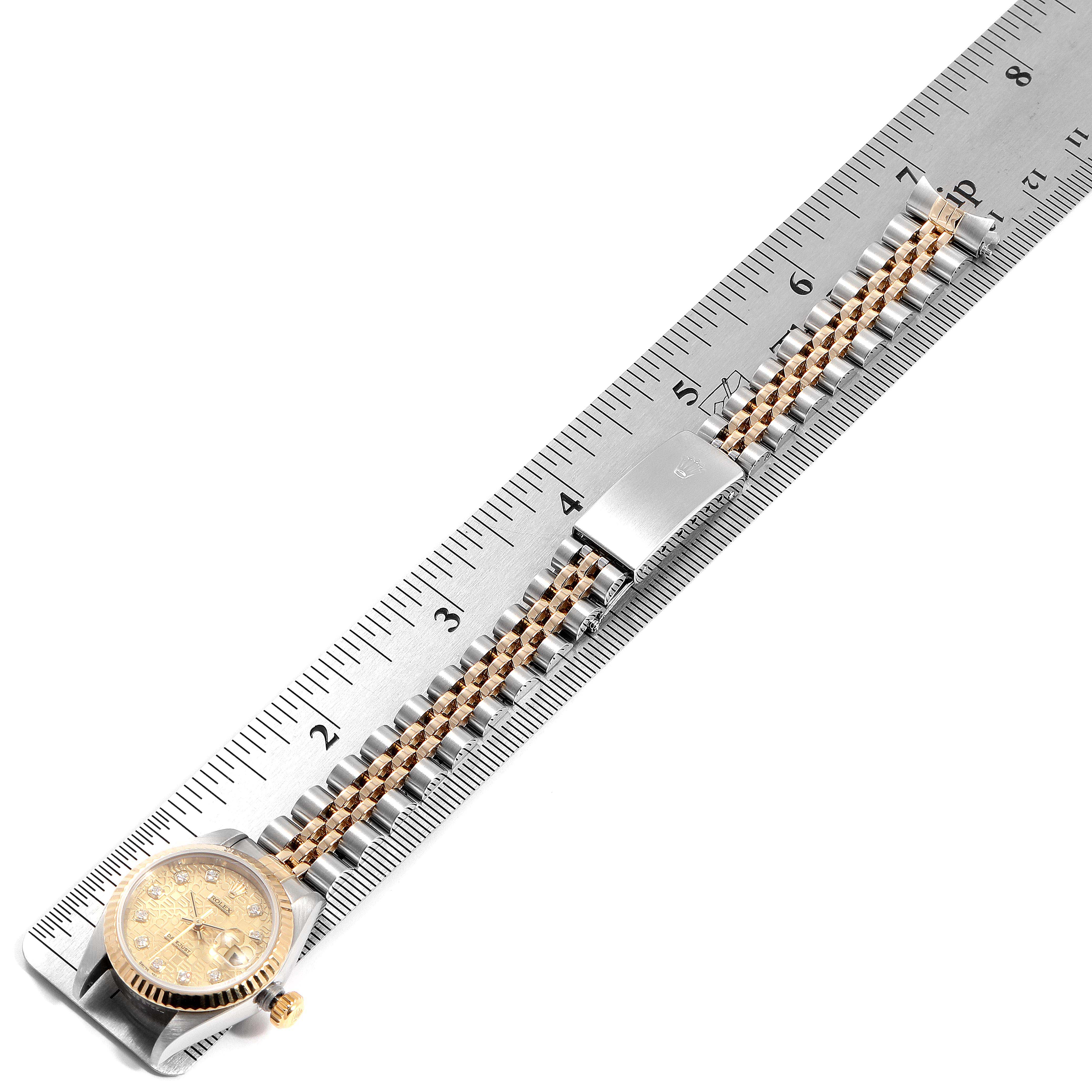 The image shows a Rolex Datejust 79173 Women's Steel and Gold (two tone) Champagne Dial 79173 Women's Steel and Gold (two tone) Champagne Dial watch laid flat next to a ruler, highlighting its band and face from a top-down angle.