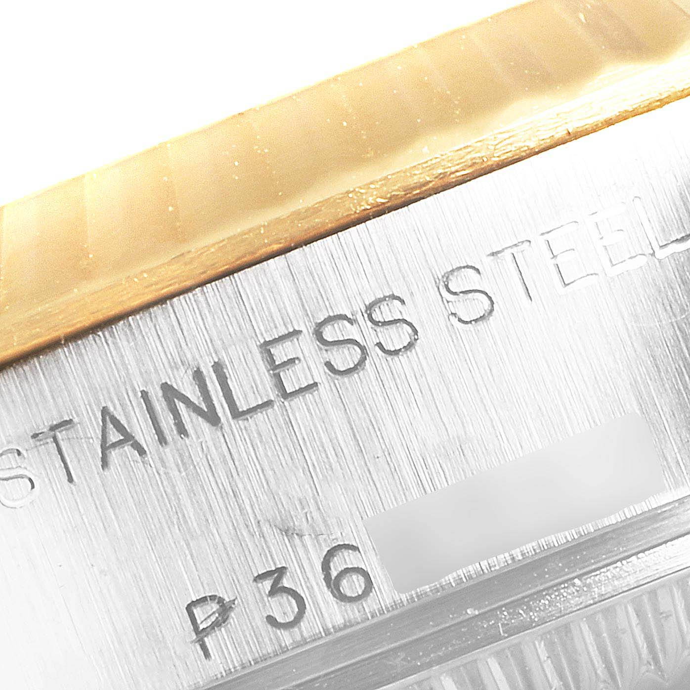 Close-up of the side of a Rolex Datejust 79173 Women's Steel and Gold (two tone) Champagne Dial 79173 Women's Steel and Gold (two tone) Champagne Dial watch, showing the stainless steel text and part of the fluted bezel.