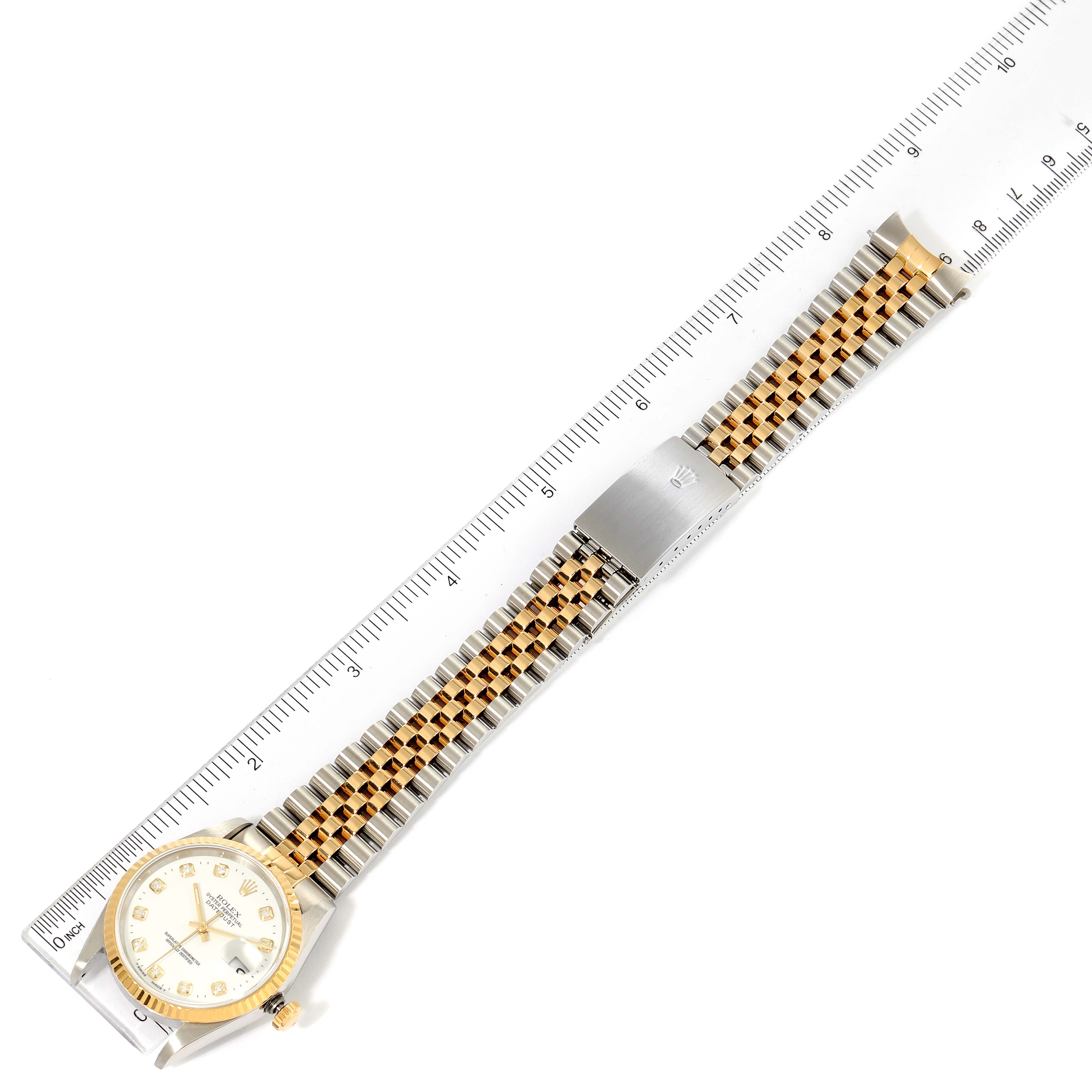 This image shows the entire Rolex Datejust 16233 Men's Steel and Gold (two tone) White Dial 16233 Men's Steel and Gold (two tone) White Dial watch laid flat next to a ruler for measurement.