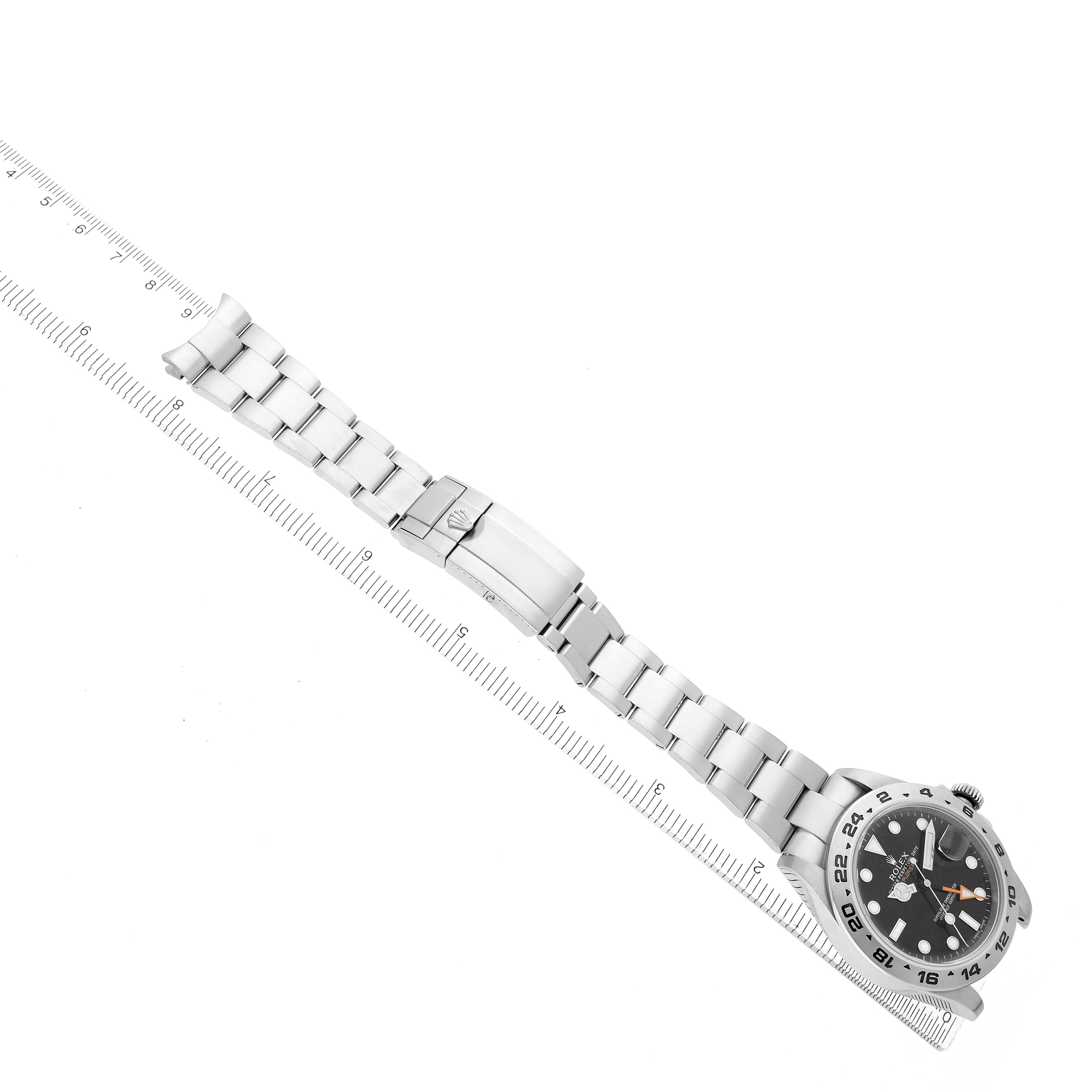 The Rolex Explorer 216570 Men
s Stainless Steel Black Dial watch is shown from an overhead angle, displaying the bracelet, clasp, and face aligned with a ruler.