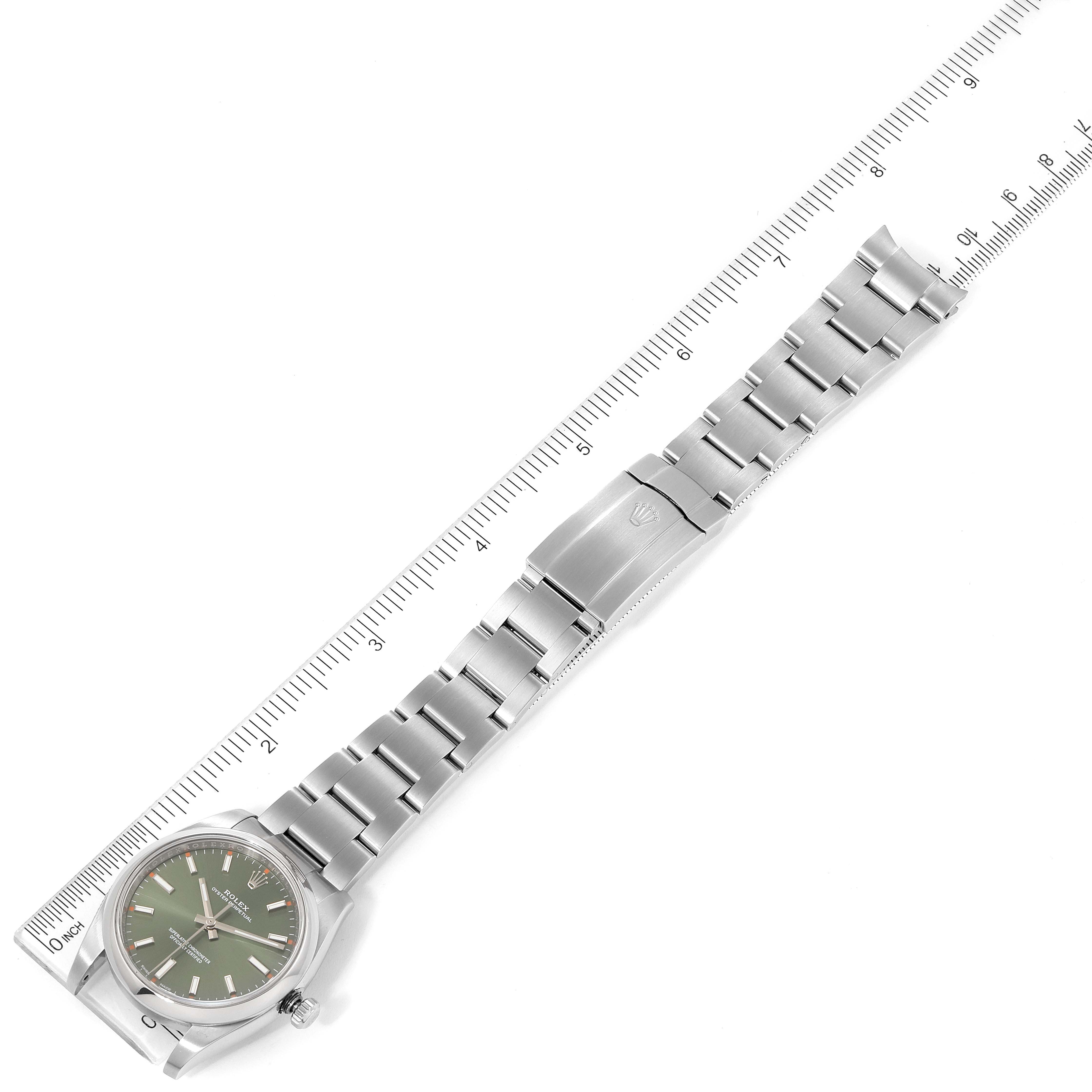 This Rolex Oyster Perpetual 114200 Men's Stainless Steel Green Dial 114200 Men's Stainless Steel Green Dial watch is photographed flat, showing the full bracelet, clasp, and green dial against a ruler.