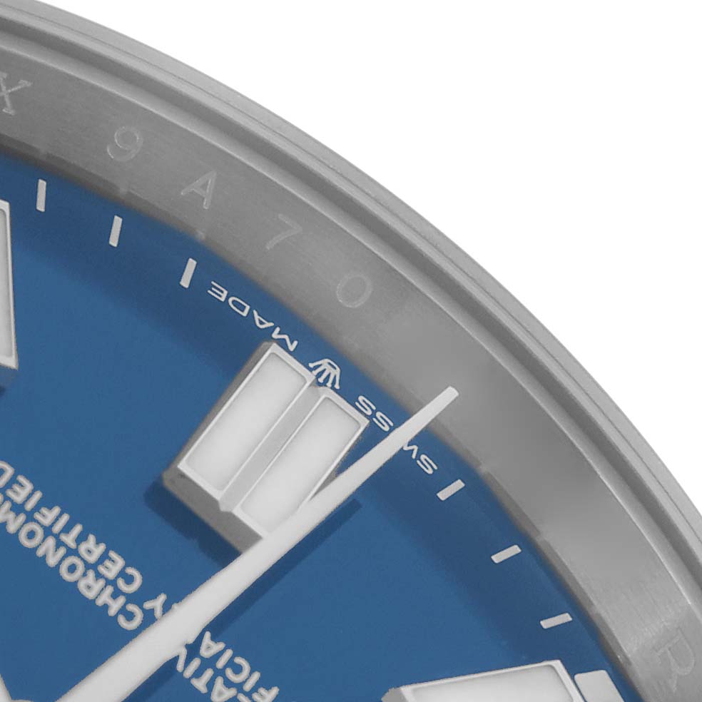 The image shows a close-up of the Rolex Oyster Perpetual 124300 Men
s Stainless Steel Blue Dial
s blue dial, highlighting markers, text, and part of the bezel.