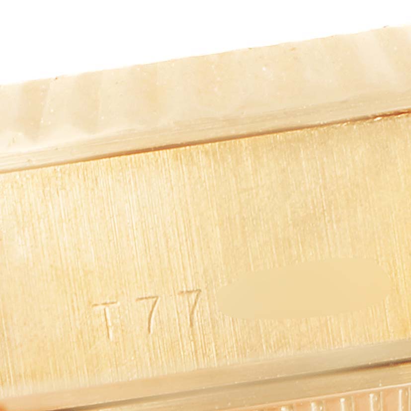This close-up image shows part of the gold case of a Rolex President 69178 Women's Yellow Gold White Dial 69178 Women's Yellow Gold White Dial model watch, including some engraved characters.