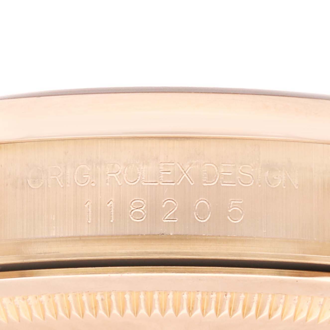 This image shows a close-up of the side of a Rolex President 118205 Men's Rose Gold White Dial 118205 Men's Rose Gold White Dial model watch with engraved text and reference number.