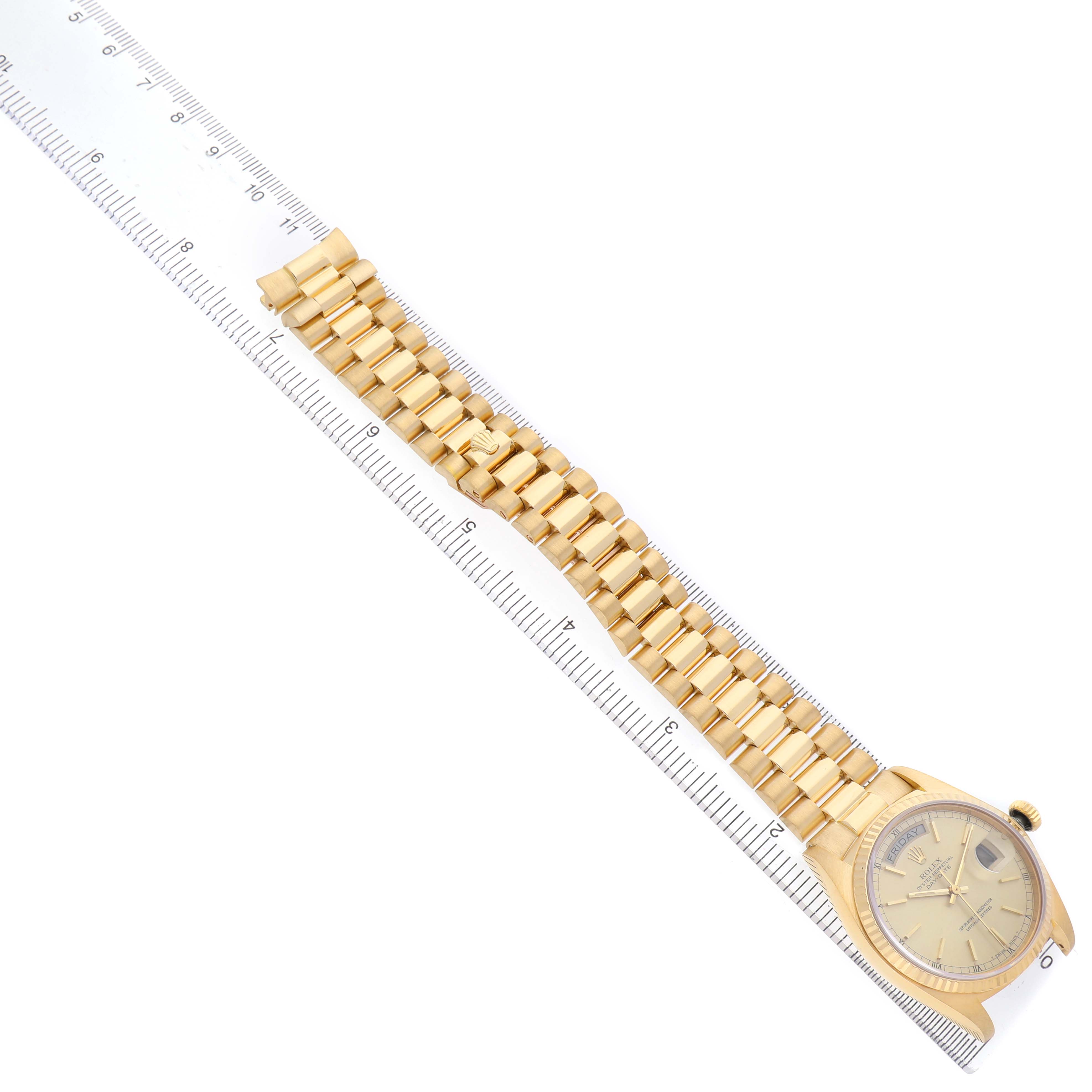The image shows a Rolex President 18038 Men's Yellow Gold Champagne Dial model watch at a top-down angle, highlighting the dial, bezel, and gold bracelet alongside a ruler.