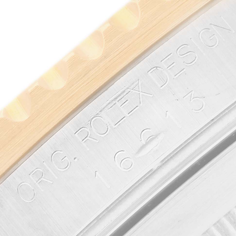 The image shows a close-up of the Rolex Submariner 16613 Men
s Steel and Gold (two tone) Black Dial
s bezel and engraved details on the side of the case.