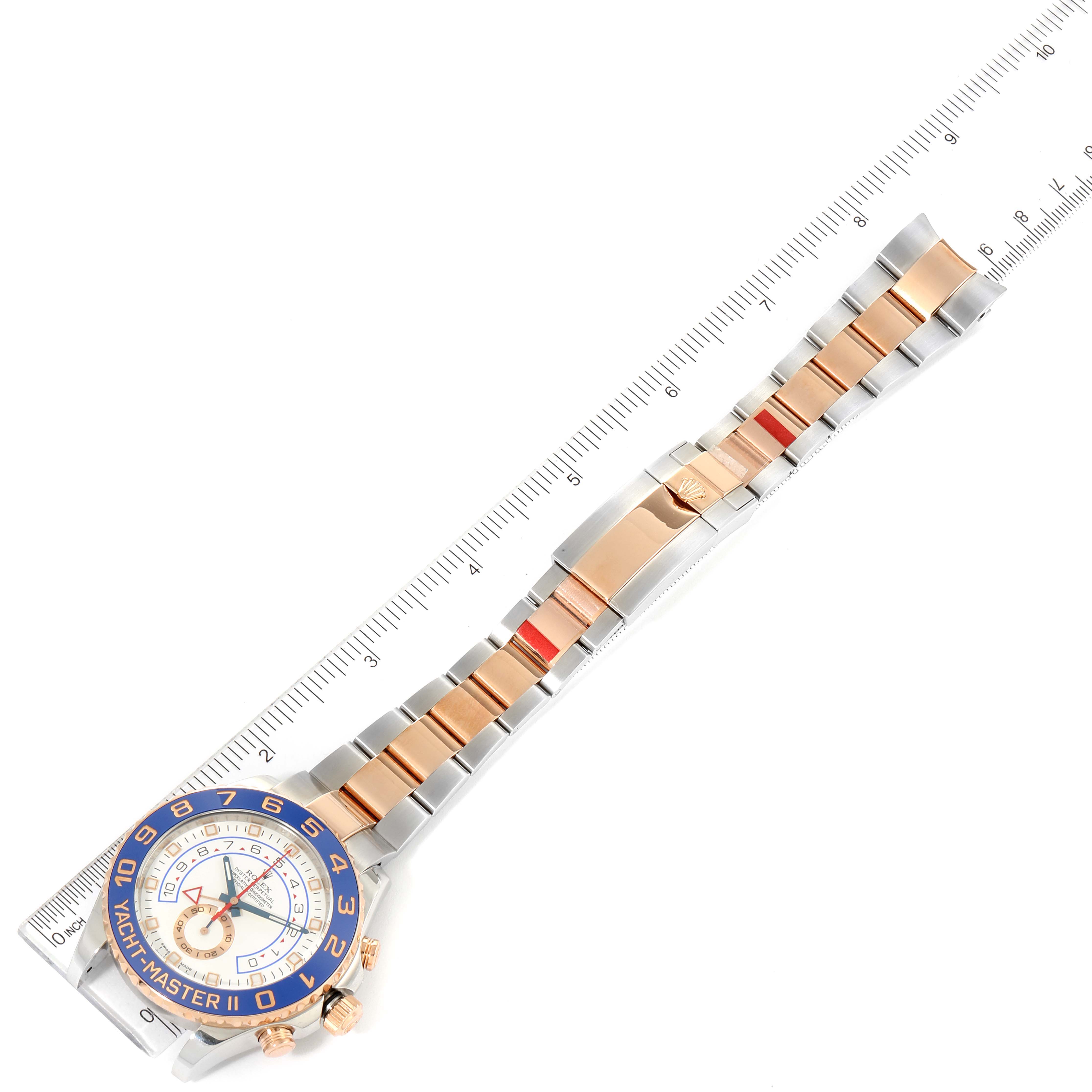 The image shows a top-down view of a Rolex Yacht-Master 116681 Men's Steel and Gold (two tone) White Dial 116681 Men's Steel and Gold (two tone) White Dial watch, including its dial, bezel, and bracelet against a measuring scale.