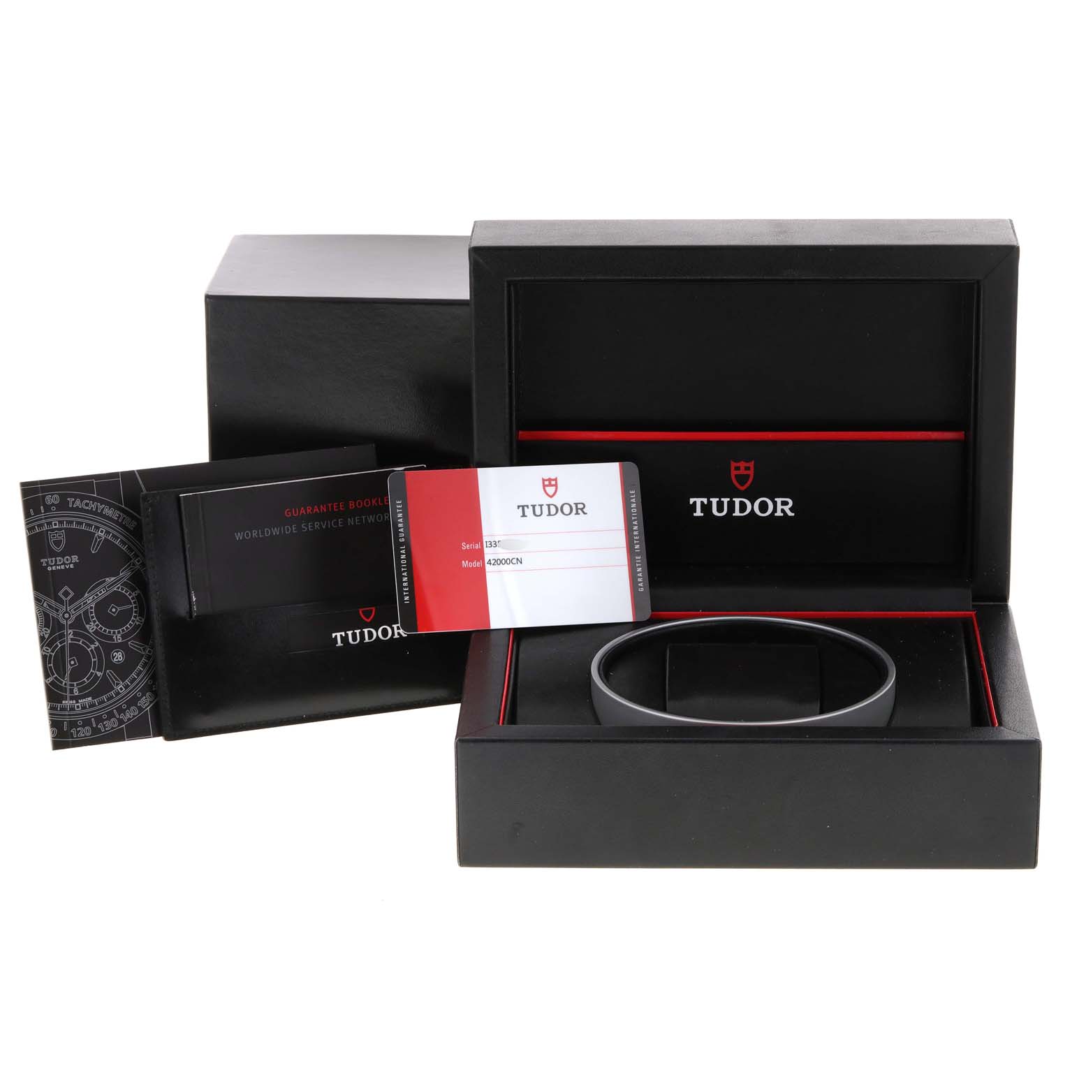 The image shows the accessories and packaging for a Tudor Fastrider 42000CN Men's Ceramic Black Dial 42000CN Men's Ceramic Black Dial watch, including the box, guarantee booklet, and warranty card.