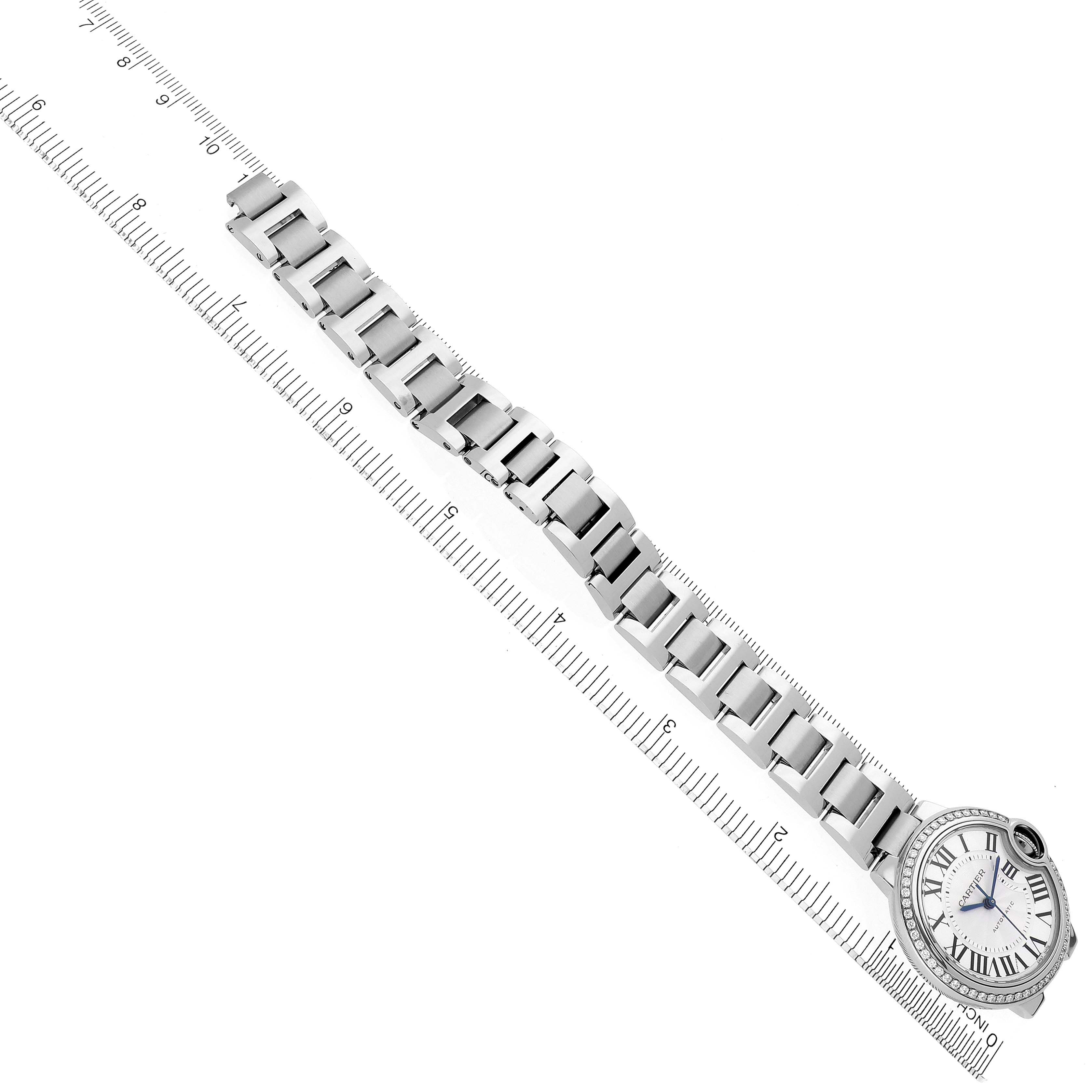 The image shows a top view of a Cartier Ballon Bleu W4BB0016 Women's Stainless Steel Silver Dial W4BB0016 Women's Stainless Steel Silver Dial watch with a full metal bracelet laid next to a ruler.