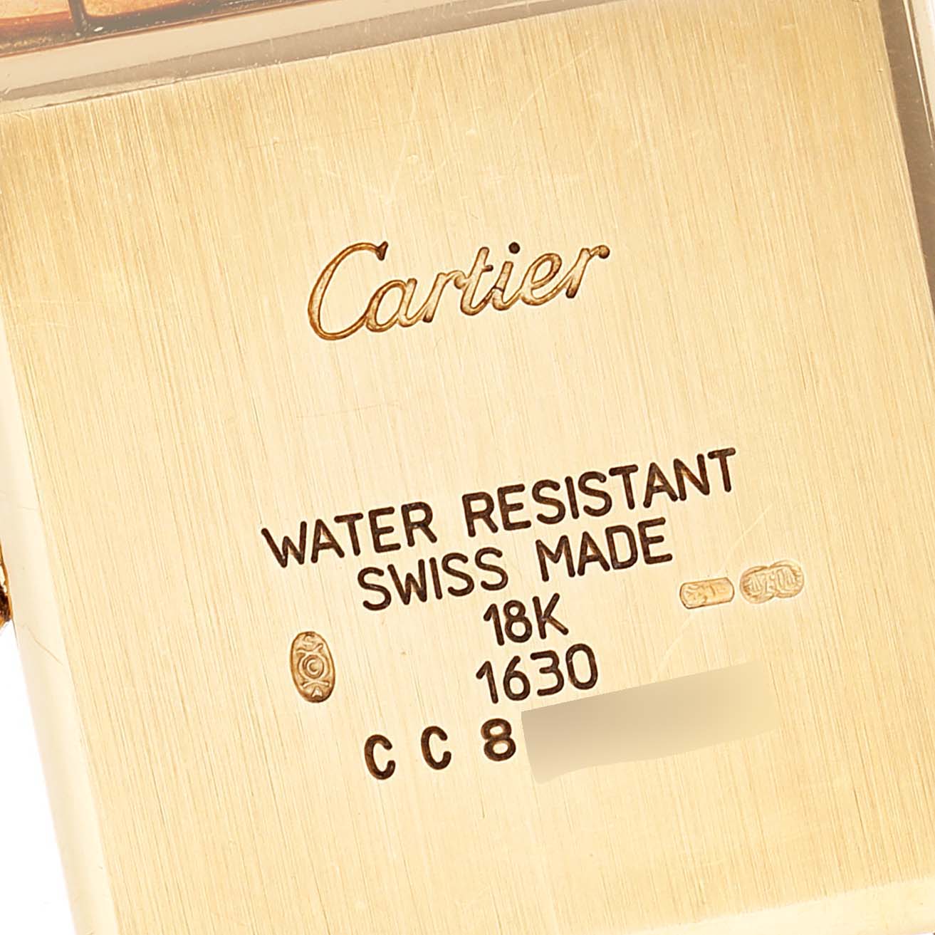 This image shows the back case details of the Cartier Tank Obus W15122N7 Women's Yellow Gold Silver Dial W15122N7 Women's Yellow Gold Silver Dial watch, highlighting its inscriptions and brand name.