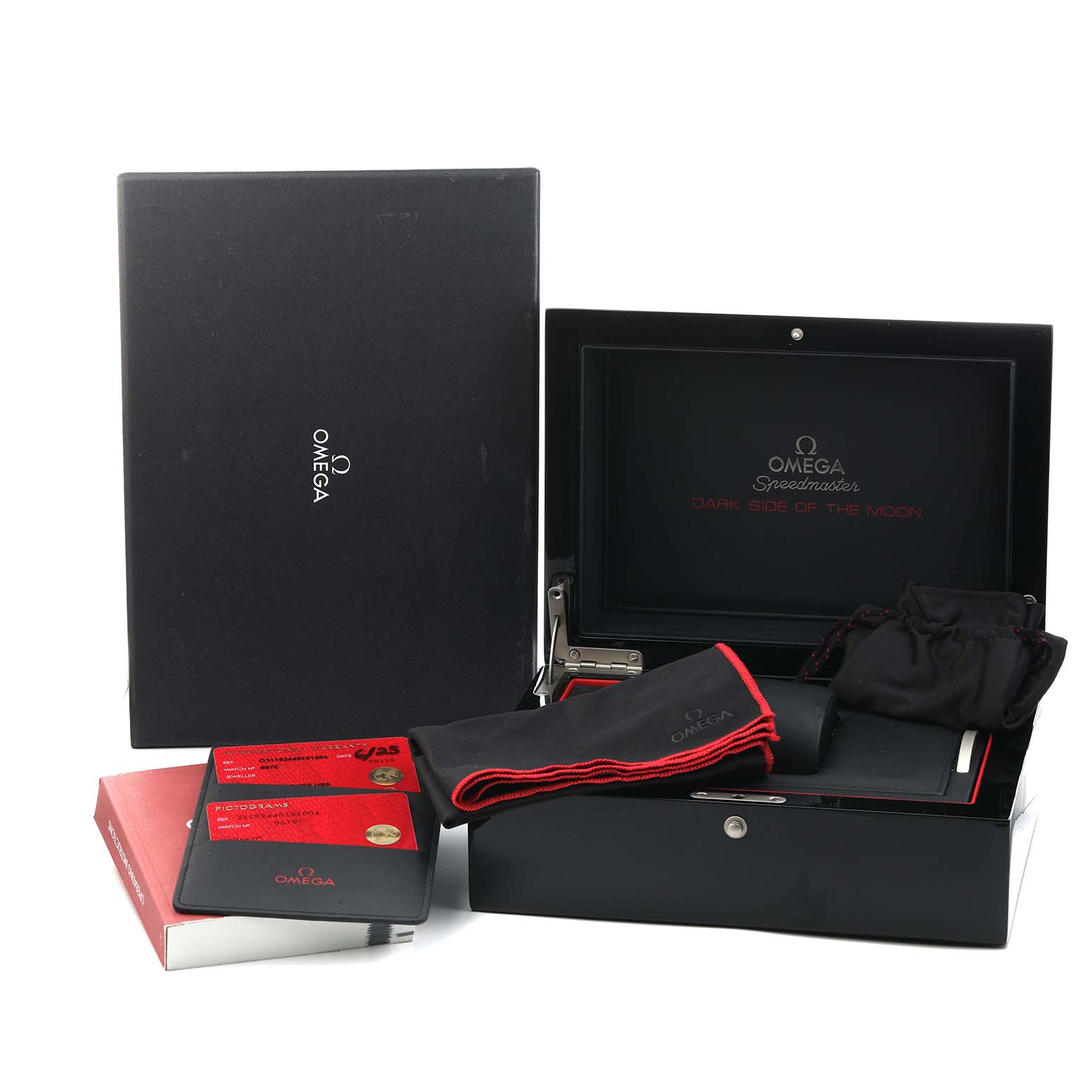 The image shows an Omega Speedmaster O311.92.44.51.01.003 Men
s Ceramic Black Dial watch box and accessories, including a cloth, cards, and a case, viewed from an angled perspective.