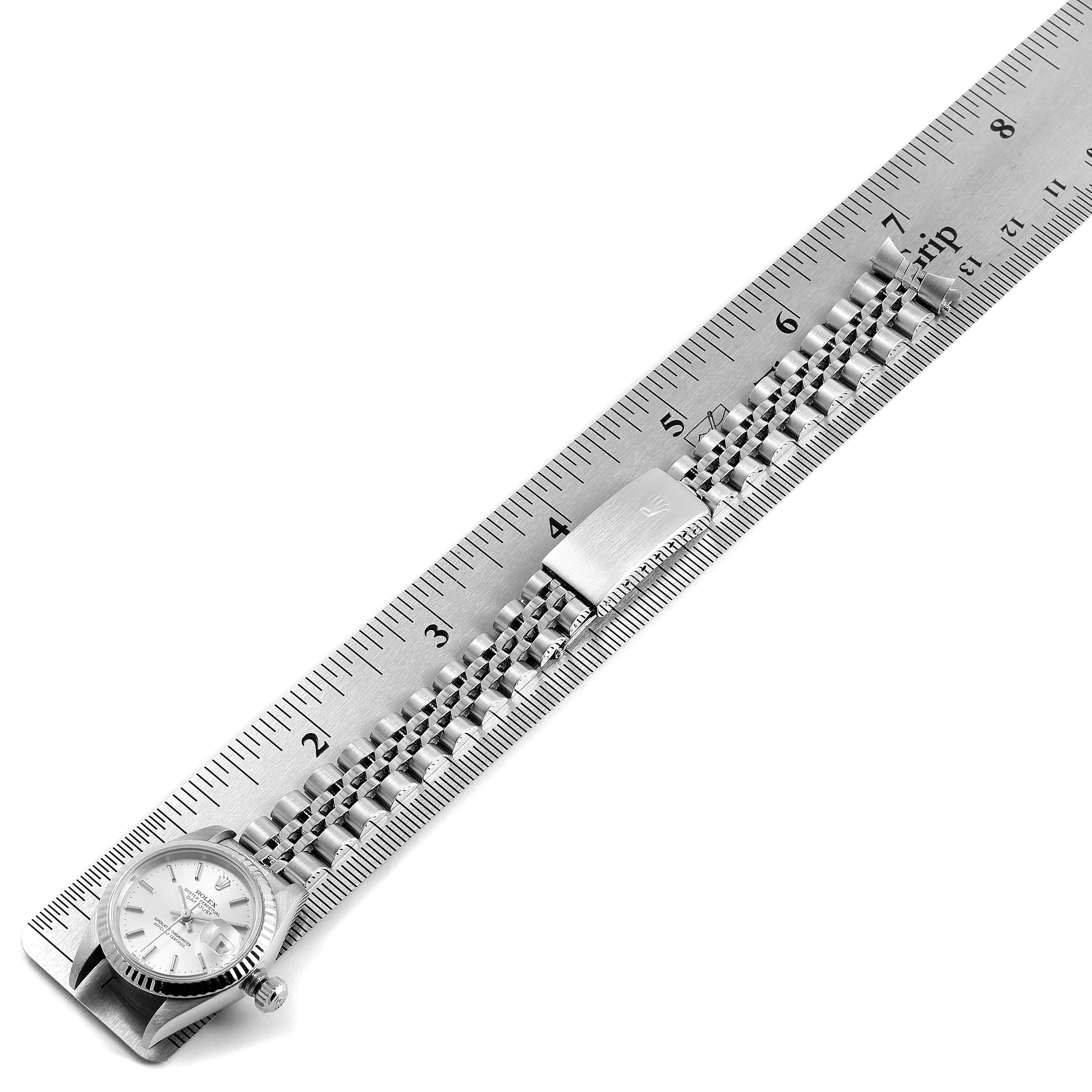 The image shows a top-down view of a Rolex Datejust 79174 Women's Stainless Steel Silver Dial 79174 Women's Stainless Steel Silver Dial watch and its metal bracelet laid next to a ruler for measurement.