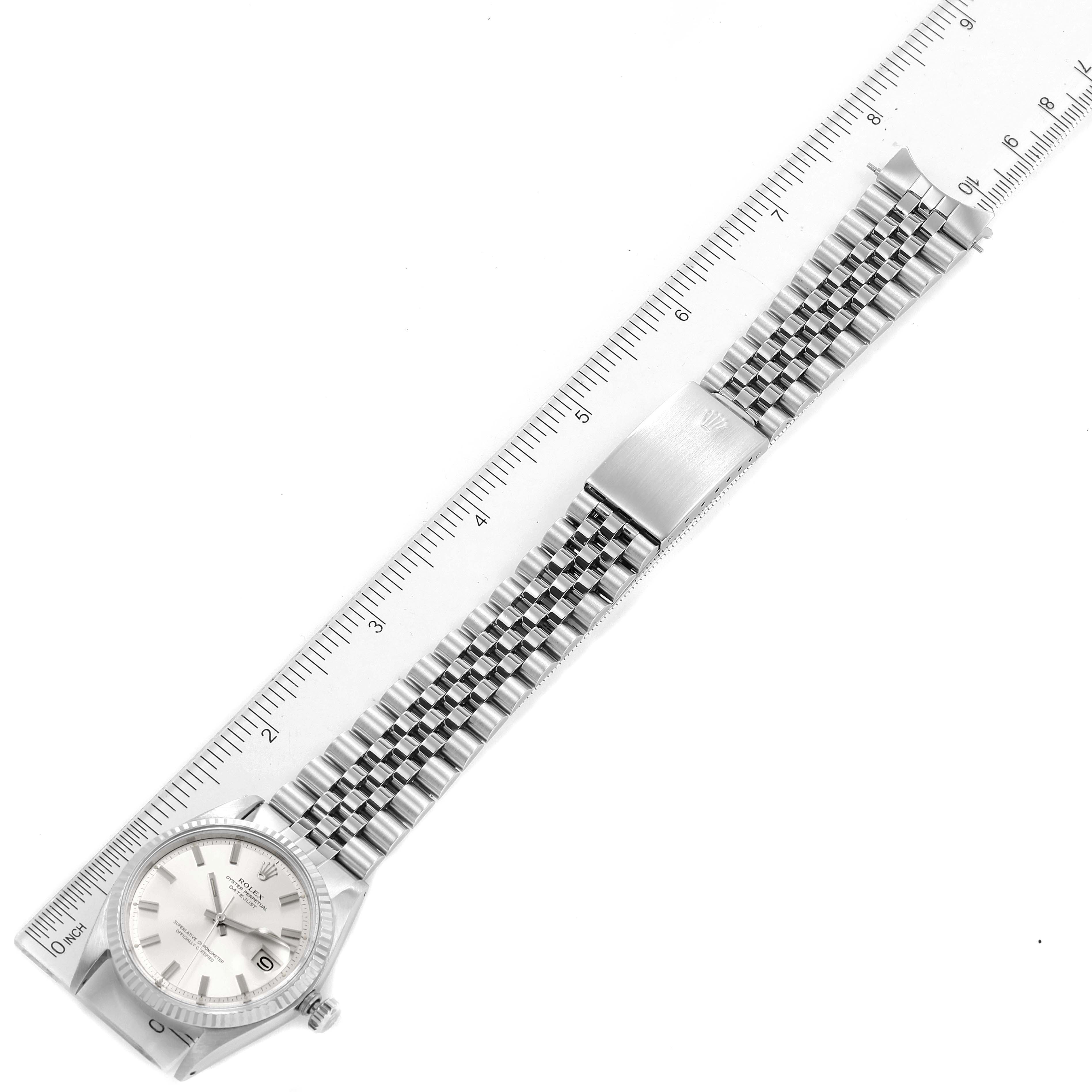 The Rolex Vintage Collection 1601 Men's Stainless Steel Silver Dial 1601 Men's Stainless Steel Silver Dial watch is shown in a top-down view, displaying the face, bracelet, and clasp next to a ruler.