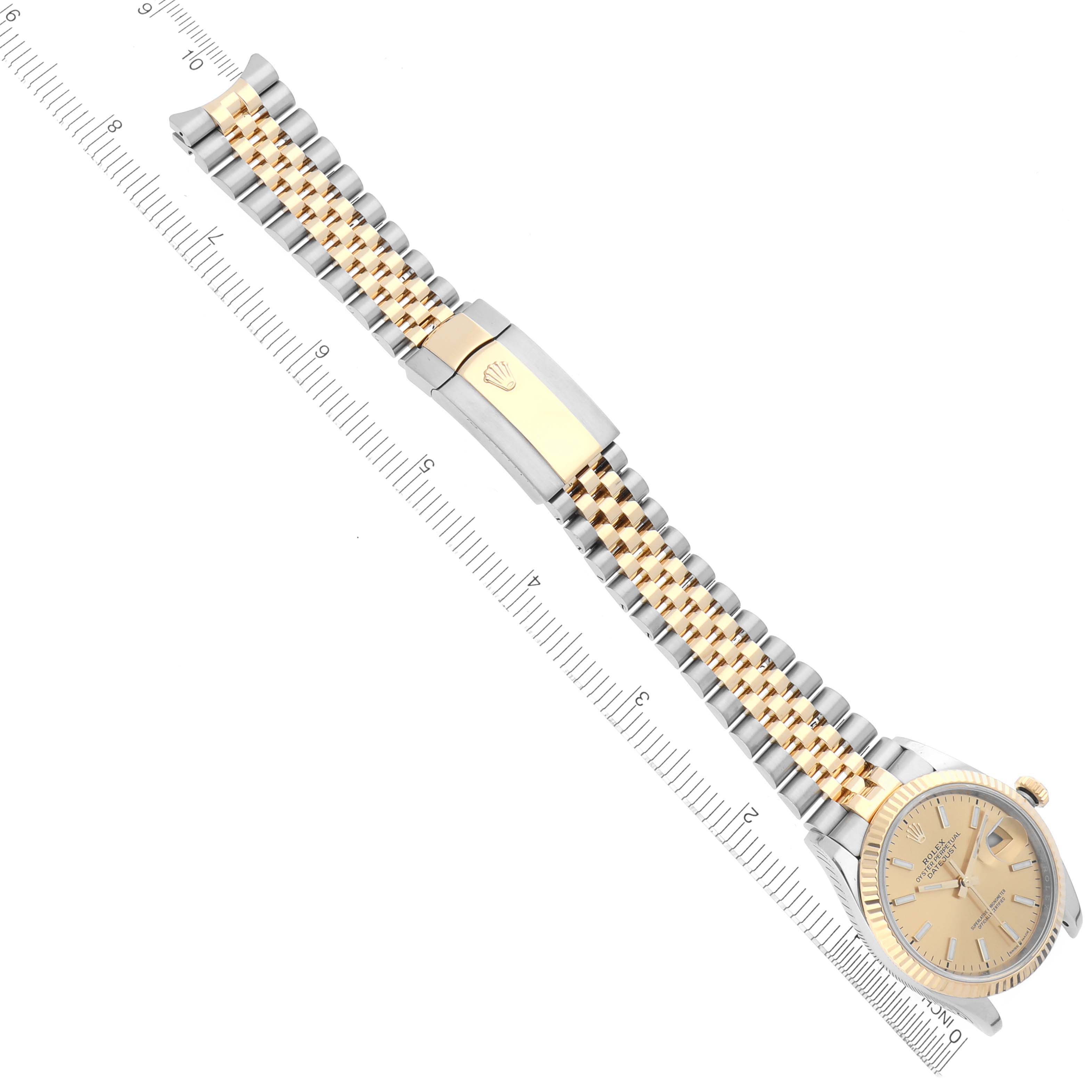 The image shows a Rolex Datejust 126233 Men
s Steel and Gold (two tone) Champagne Dial 126233 Men
s Steel and Gold (two tone) Champagne Dial watch laid flat with its bracelet extended and a ruler for scale.