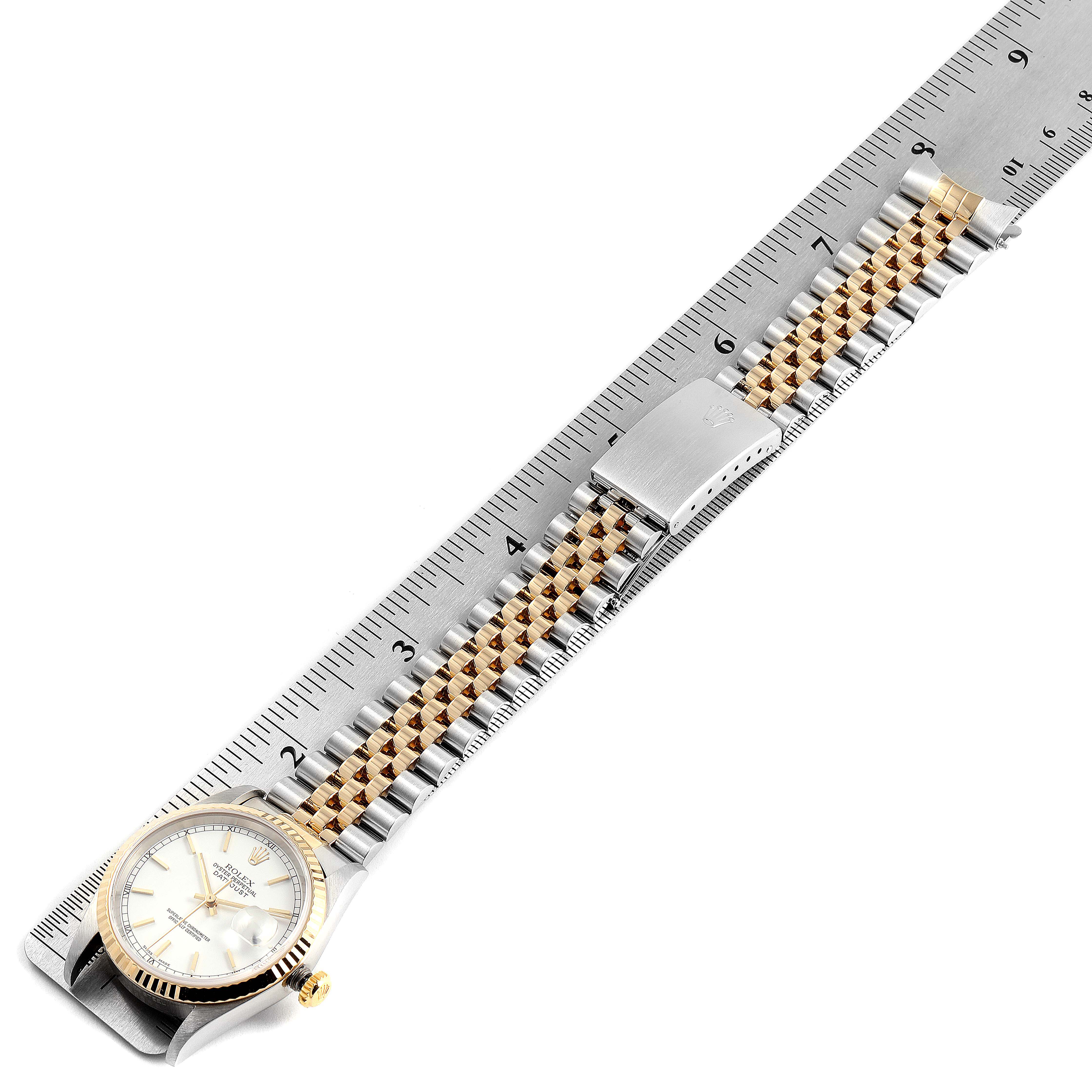 This image shows the Rolex Datejust 16233 Men
s Steel and Gold (two tone) White Dial 16233 Men
s Steel and Gold (two tone) White Dial watch laid flat with its face, bezel, and bracelet against a ruler for scale.