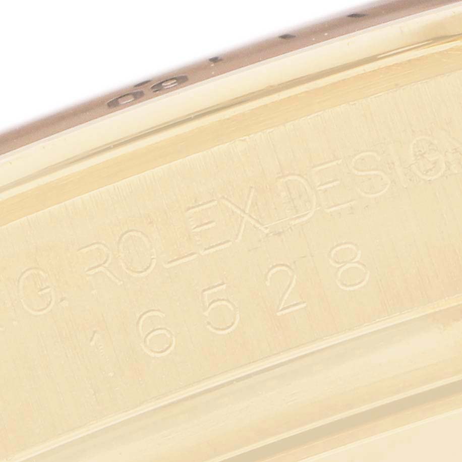 The image shows a close-up of the engraved inner bezel of the Rolex Daytona 16528 Men
s Yellow Gold Black Dial watch.