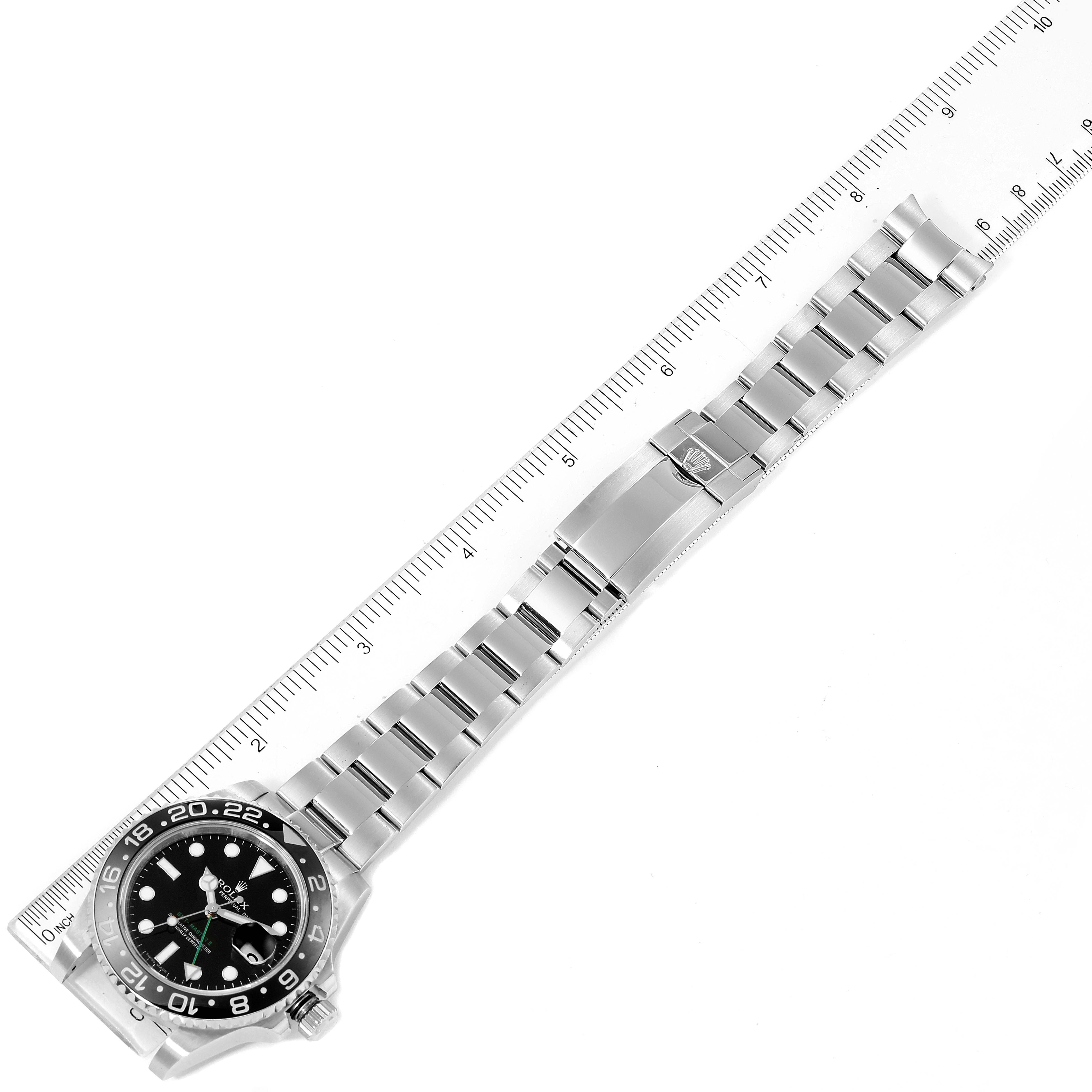 The image shows a Rolex GMT-Master 116710 Men
s Stainless Steel Black Dial 116710 Men
s Stainless Steel Black Dial watch positioned alongside a ruler, highlighting the watch case, dial, and metal bracelet.