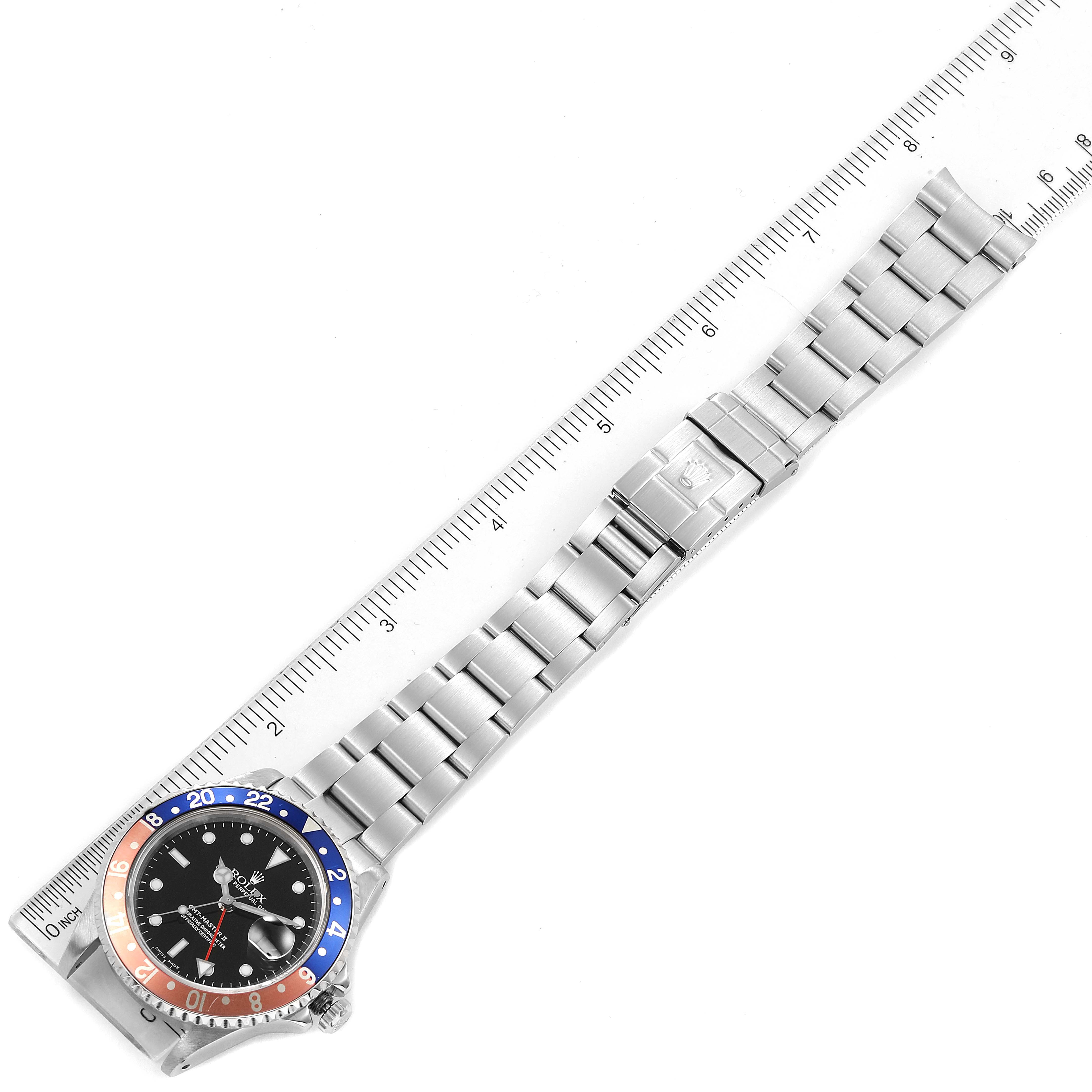The image shows a Rolex GMT-Master 16710 Men
s Stainless Steel Black Dial 16710 Men
s Stainless Steel Black Dial watch at a top-down angle with its bracelet fully extended and a ruler for scale.