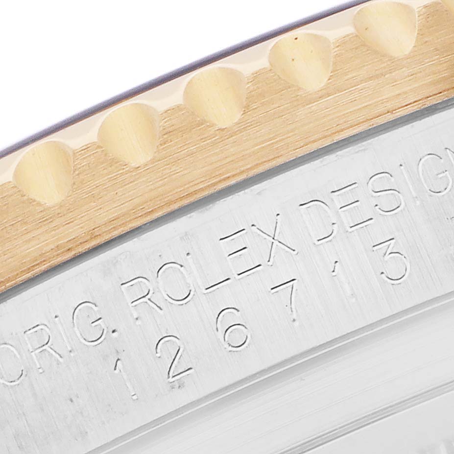 The image shows a close-up of the engraved side and bezel teeth of a Rolex GMT-Master 126713 Men
s Steel and Gold (two tone) Black Dial watch.