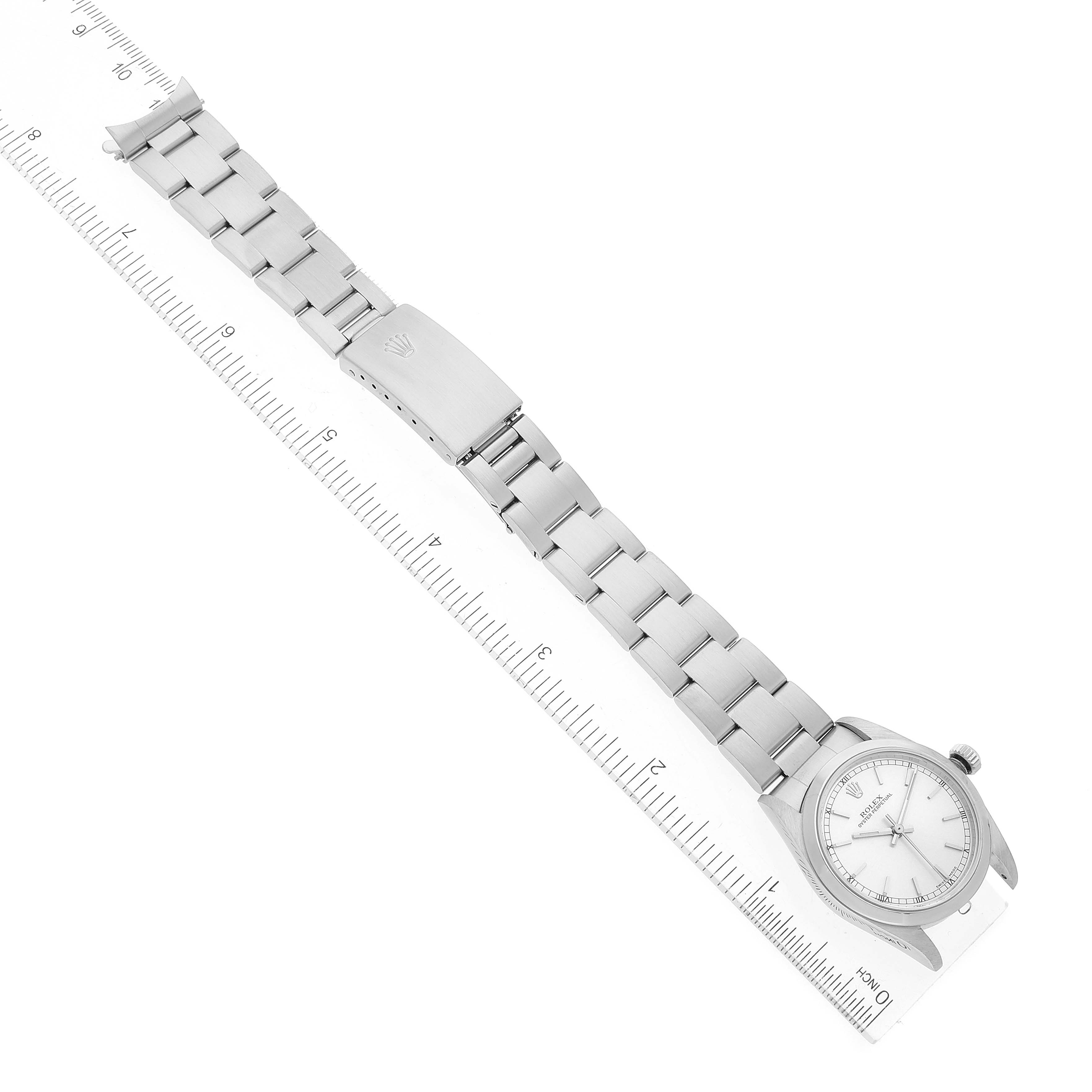 The image shows a top view of a Rolex Mid-Size 77080 Women
s Stainless Steel Silver Dial 77080 Women
s Stainless Steel Silver Dial watch, highlighting its full bracelet and clasp alongside a ruler for scale.